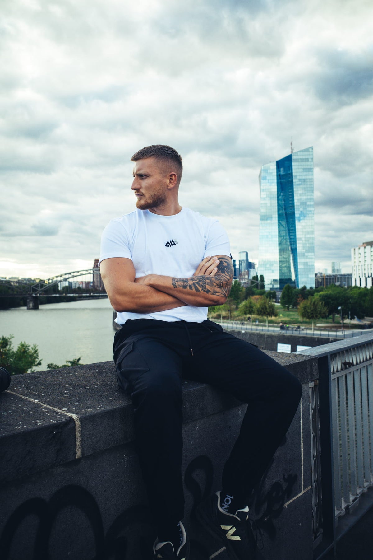 Profilansicht Mann im weißen Avantura T-Shirt mit Brustlogo vor Skyline