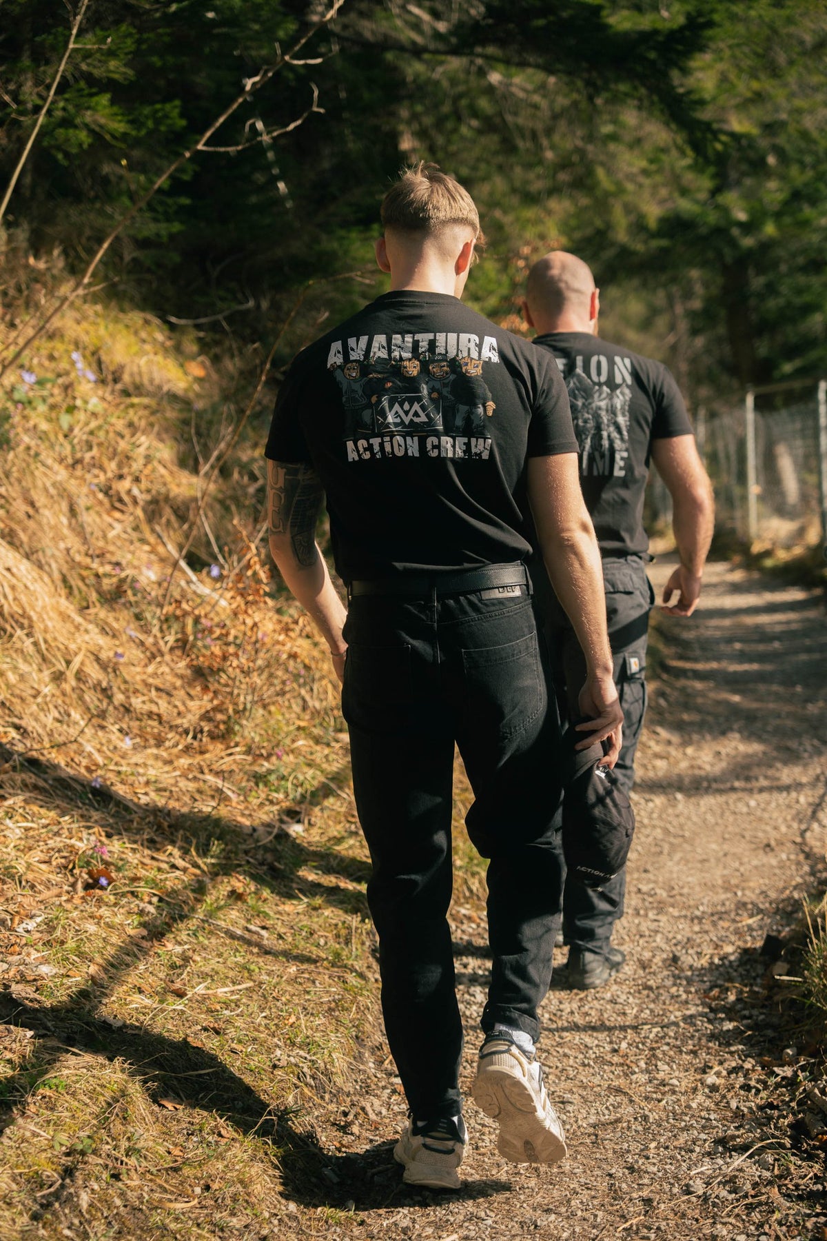 Men walking in black Action Crew T-shirts with illustrated back graphics