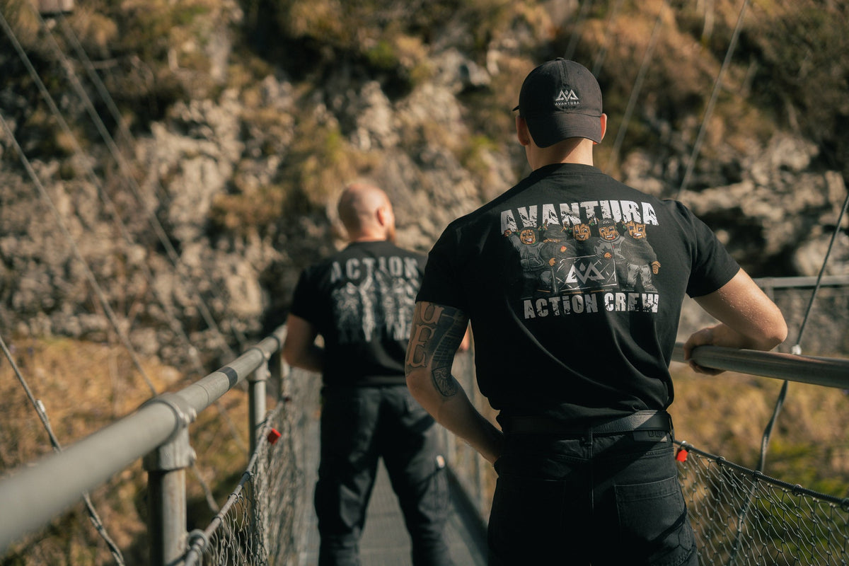 Two men wearing black Action Crew T-shirts with graphic back prints outdoors