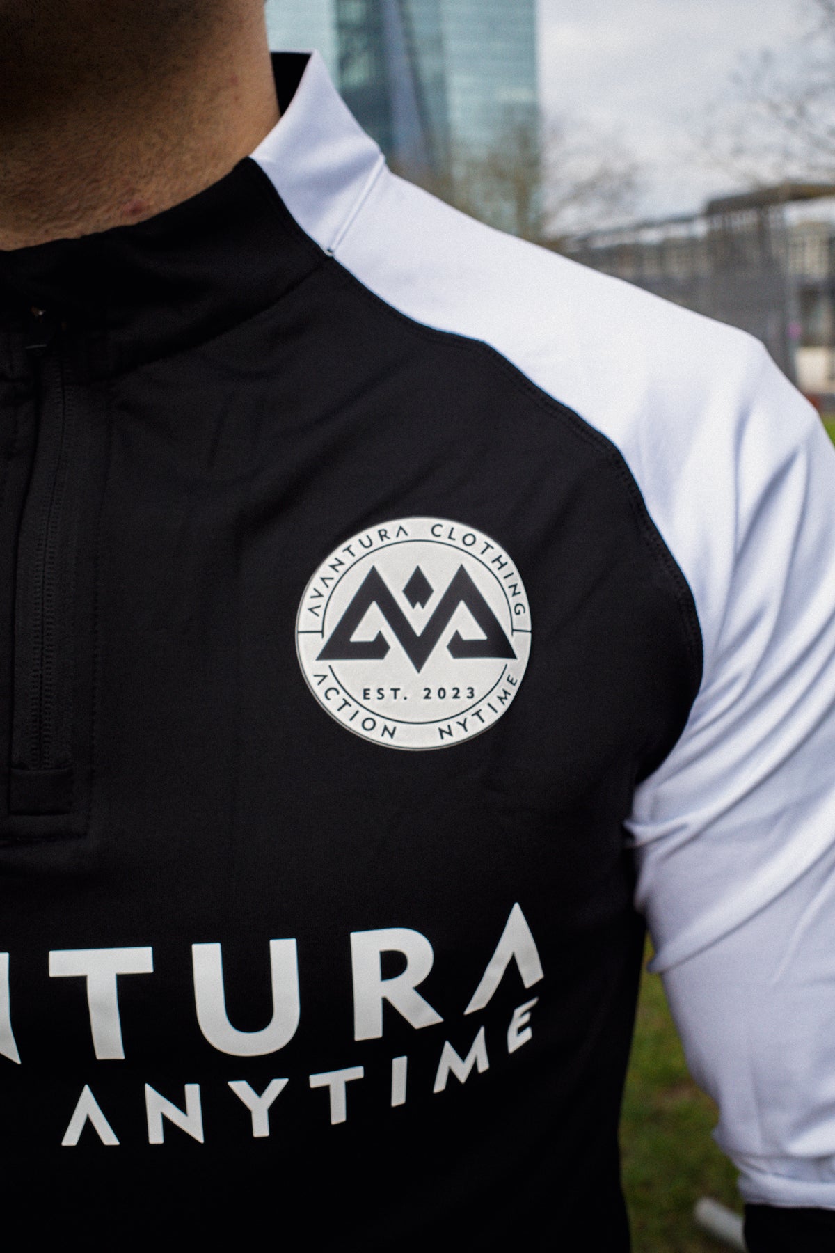 Detailaufnahme rundes Silikon-Patch Logo AVANTURA CLOTHING auf Halfzip-Sweater
