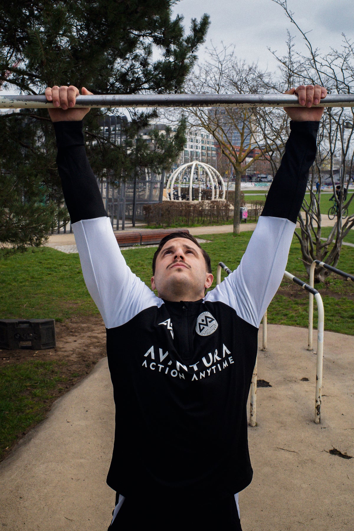 Schwarz-weißer Halfzip-Sweater mit AVANTURA ACTION ANYTIME Aufdruck beim Training im Park