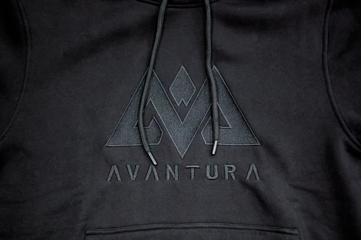 Nahaufnahme des gestickten geometrischen Logos und Schriftzugs auf dem schwarzen Hoodie