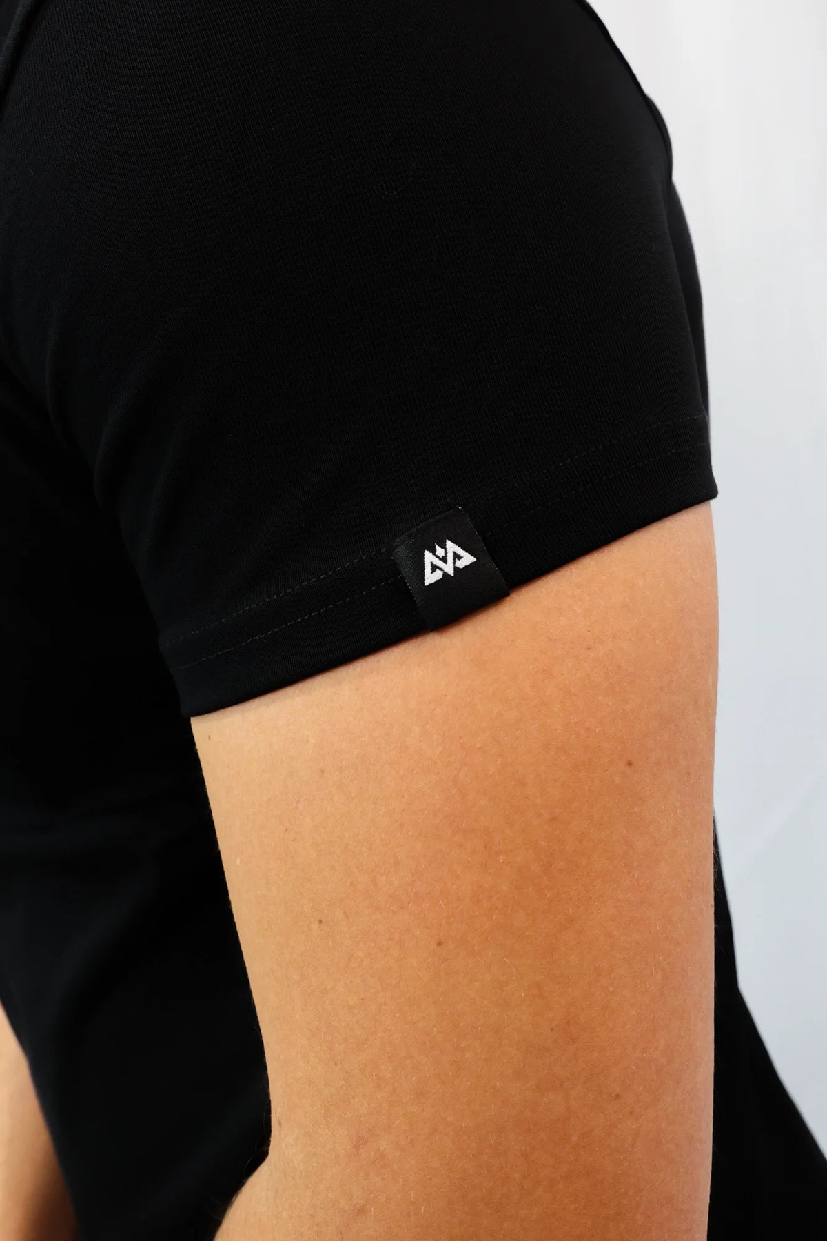 Detail of woven label with geometric logo on black T-shirt sleeve cuff