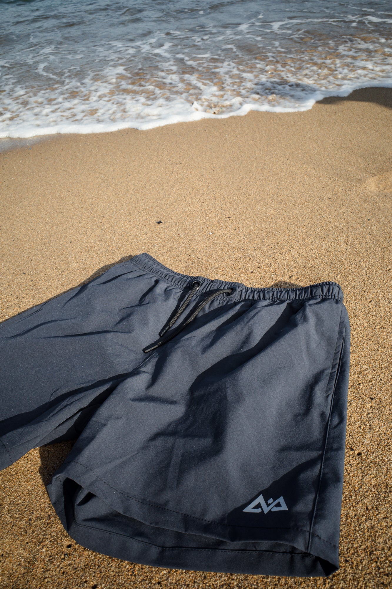 Crumpled navy swim trunks on wet sand