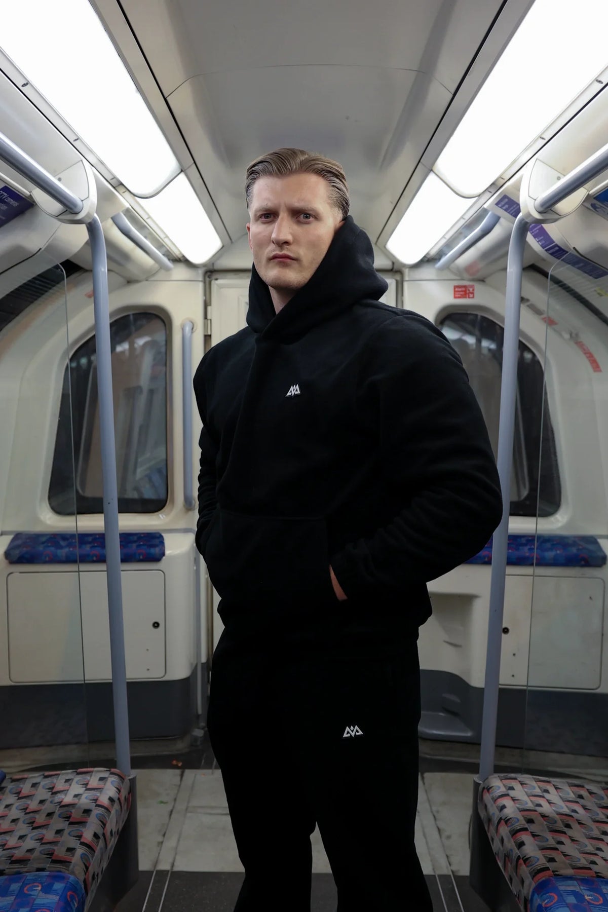Black fleece joggers with hood up in subway car