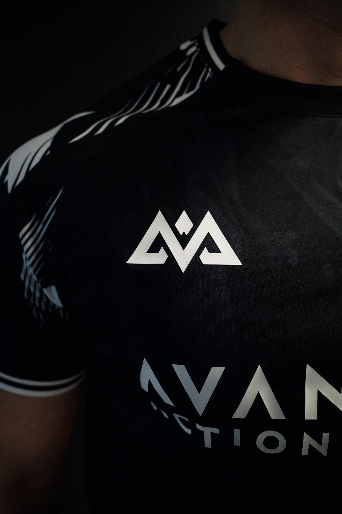 Front chest close-up of geometric logo and partial text on jersey
