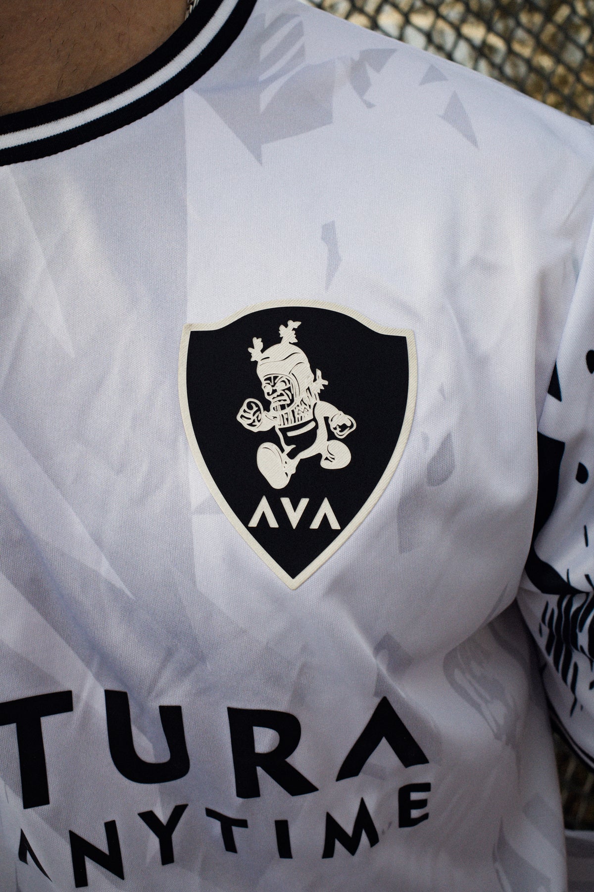 Macro shot of black silicone shield patch with goblin illustration on white Avantura jersey chest