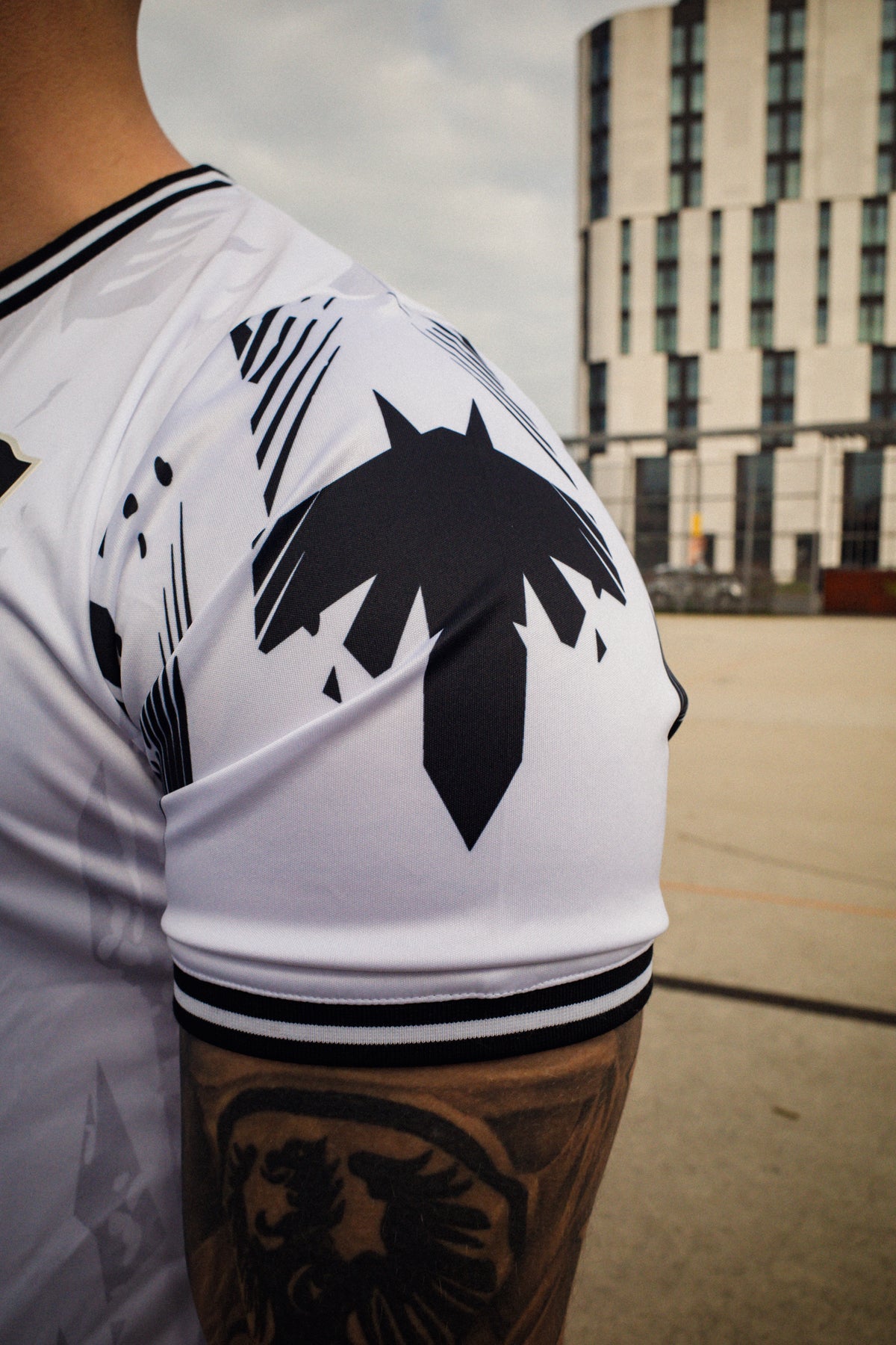 Side close-up of white Avantura jersey sleeve with bold black brushstroke graphics and striped cuff