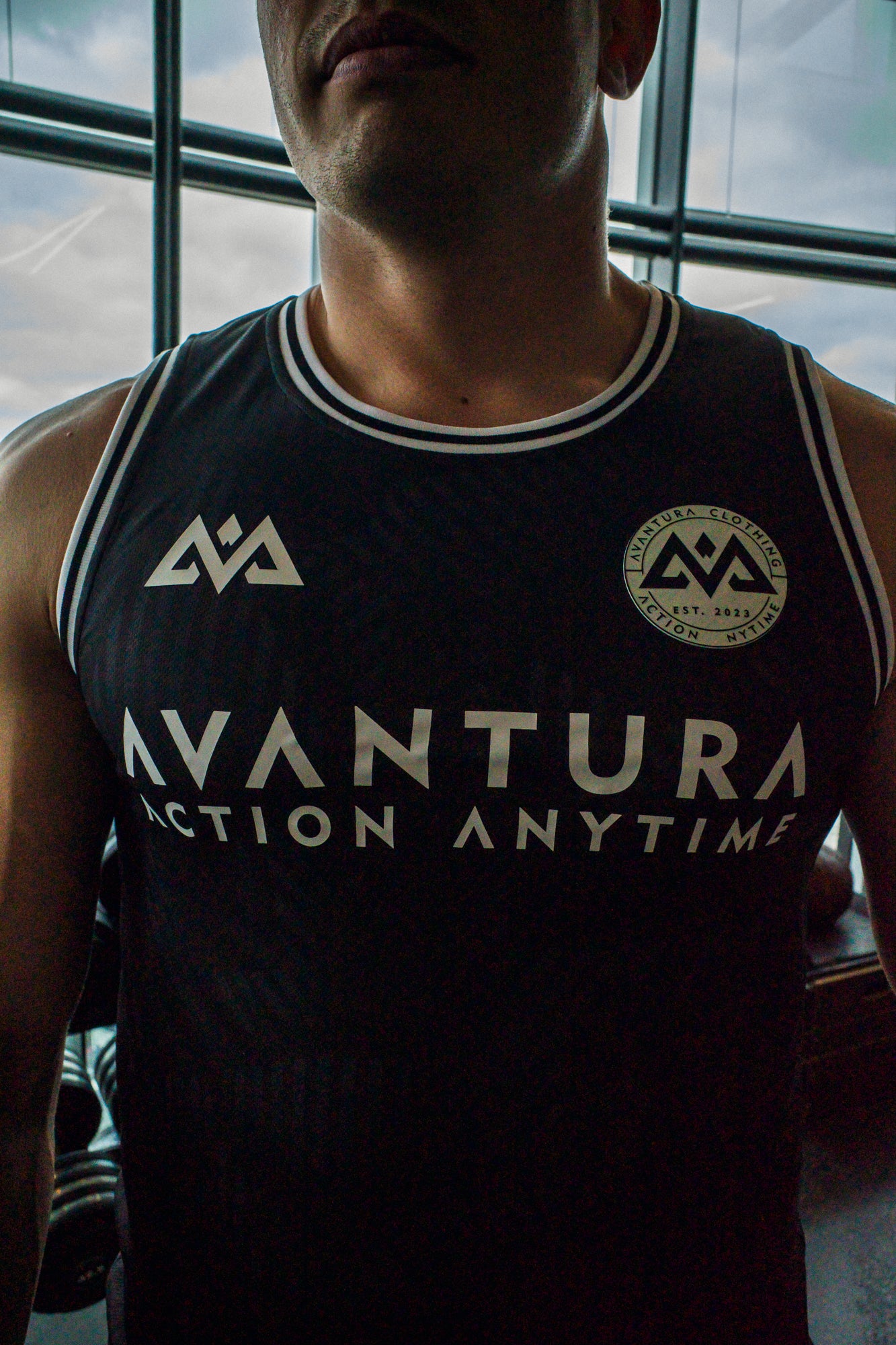 Detail of bold white Action Anytime text and logos on black Avantura tank top