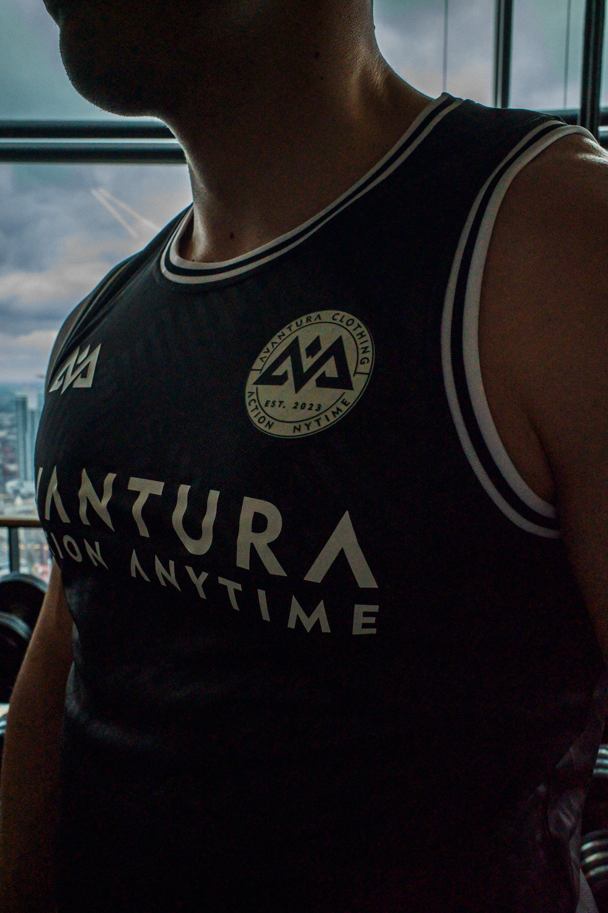 Close-up of circular Avantura Clothing emblem on black tank top chest