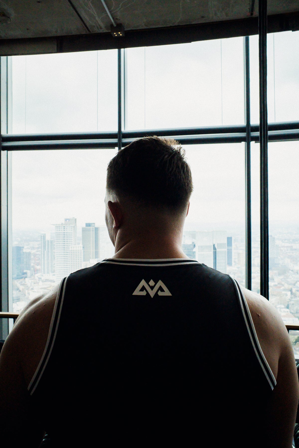 Back view of black Avantura tank top showing geometric logo and fitted fit