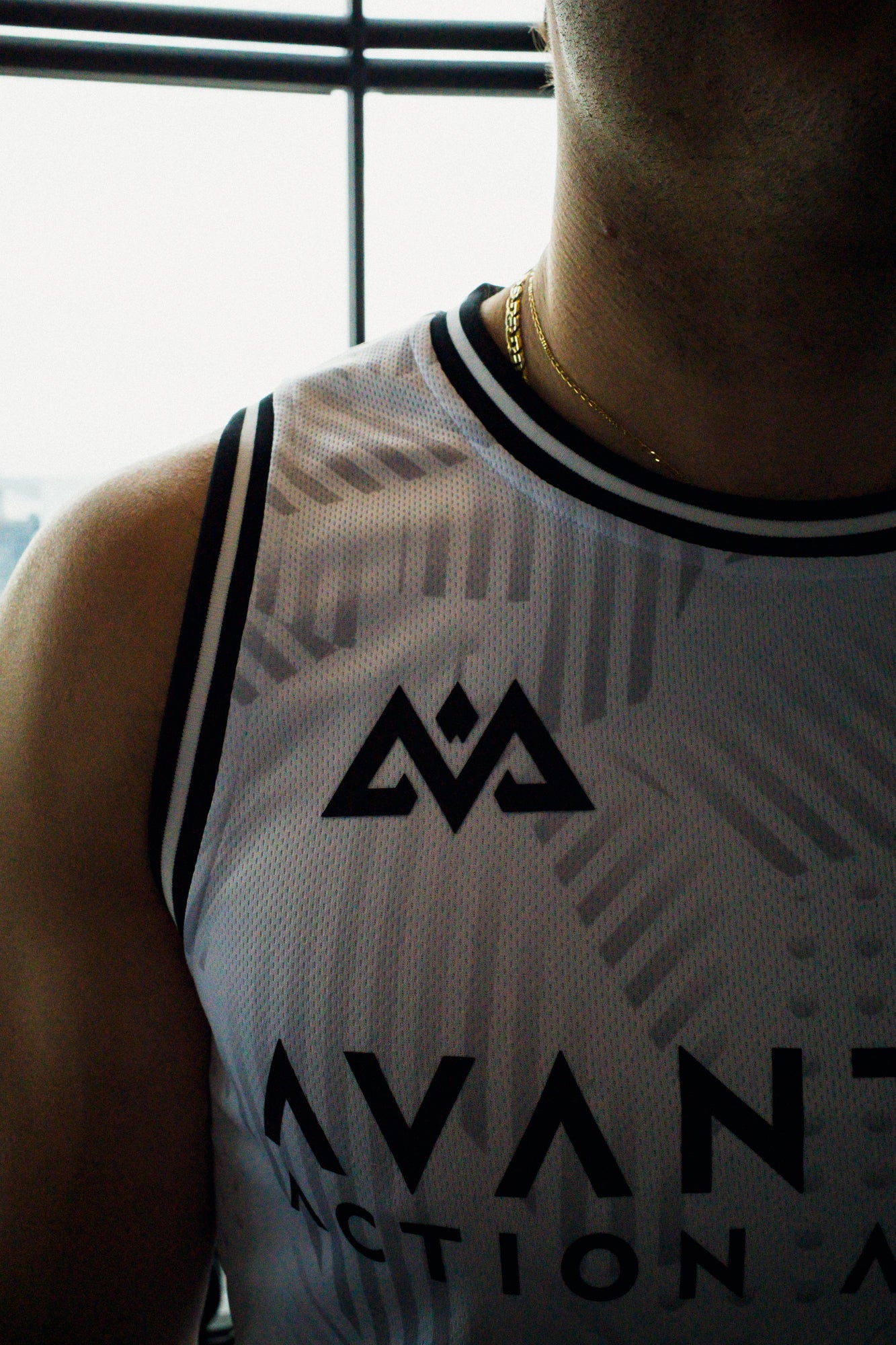 Close-up of ribbed neck trim and geometric logo on white tank top