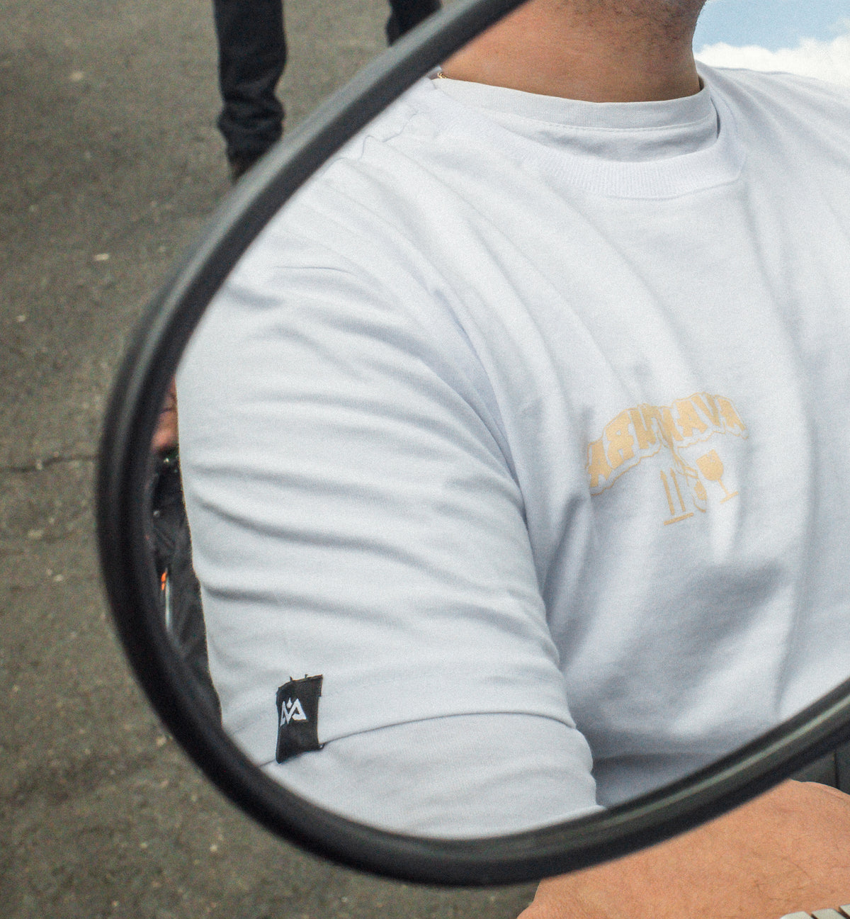 Close-up of white t-shirt sleeve label and chest logo in mirror