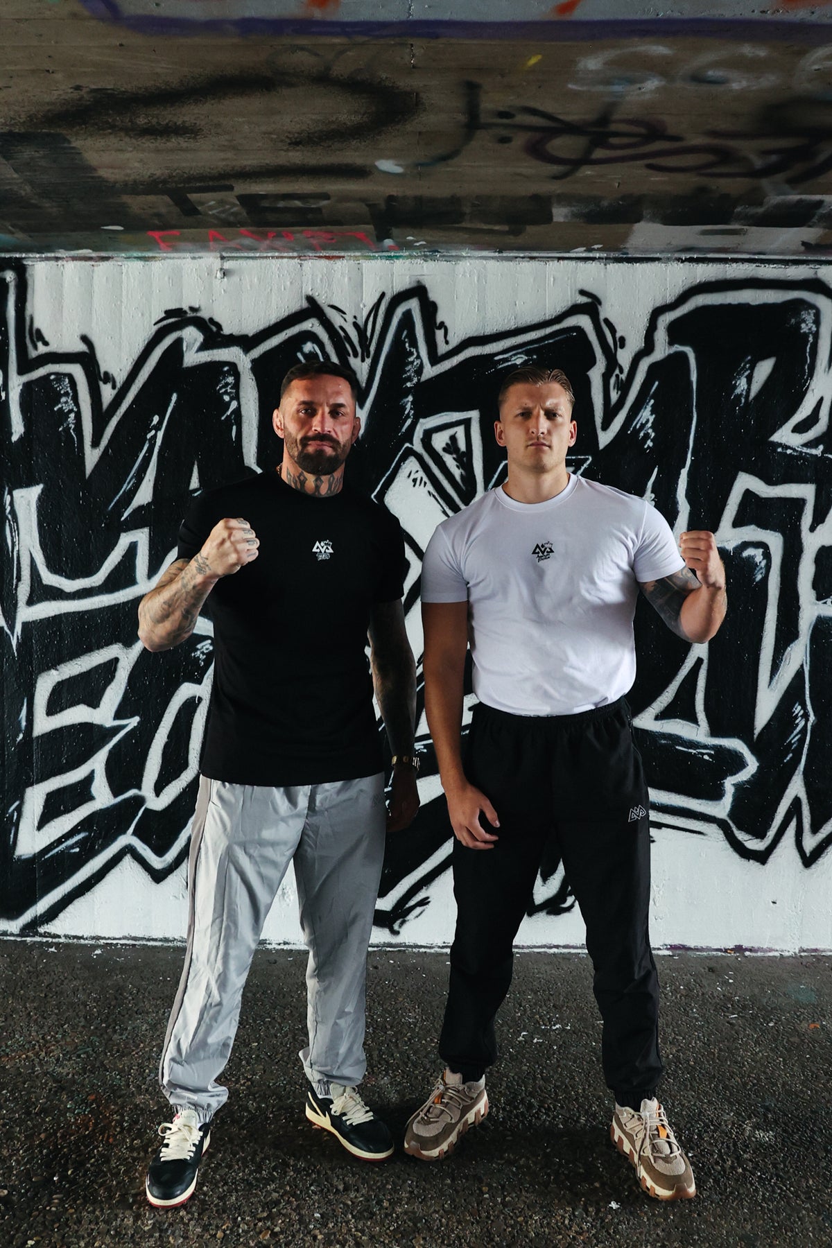 Black Avantura t-shirt with white chest logo worn by tattooed man in streetwear style