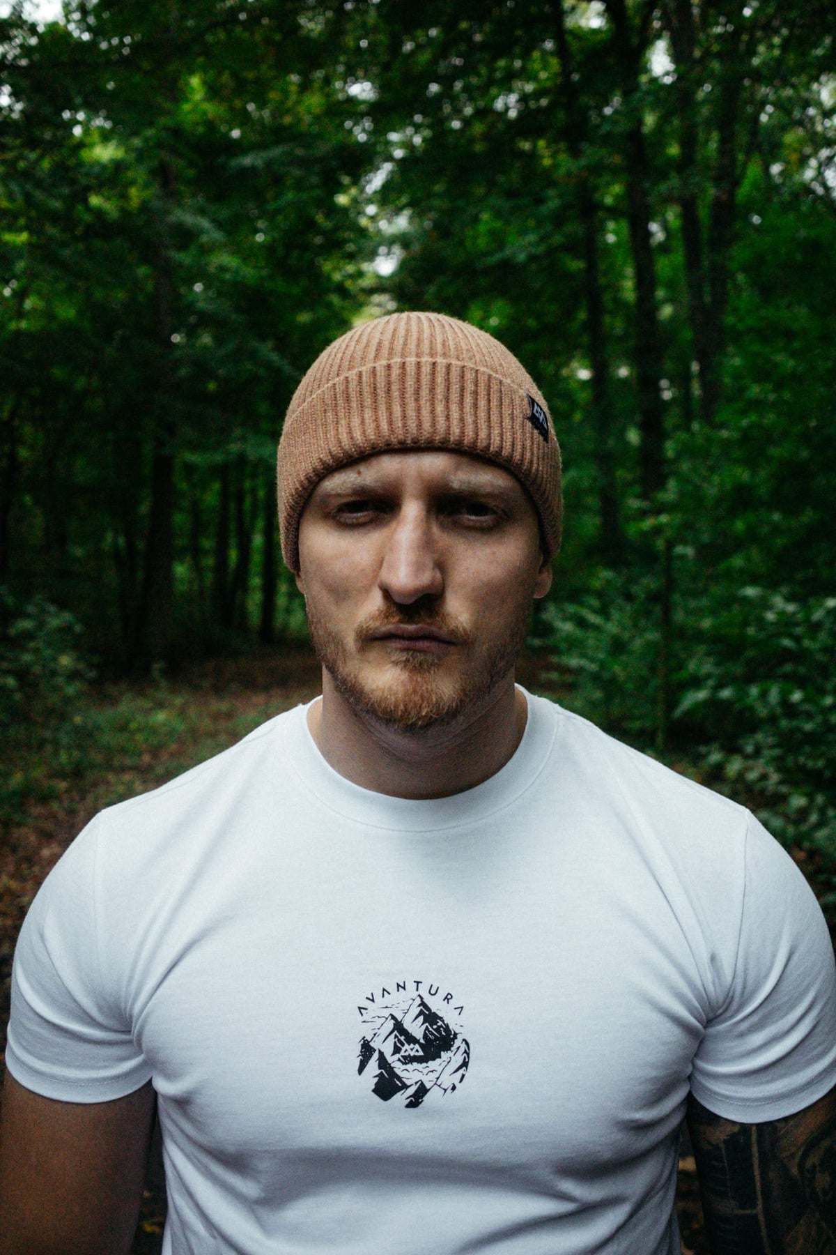Front view of man wearing beige knit beanie and white t-shirt