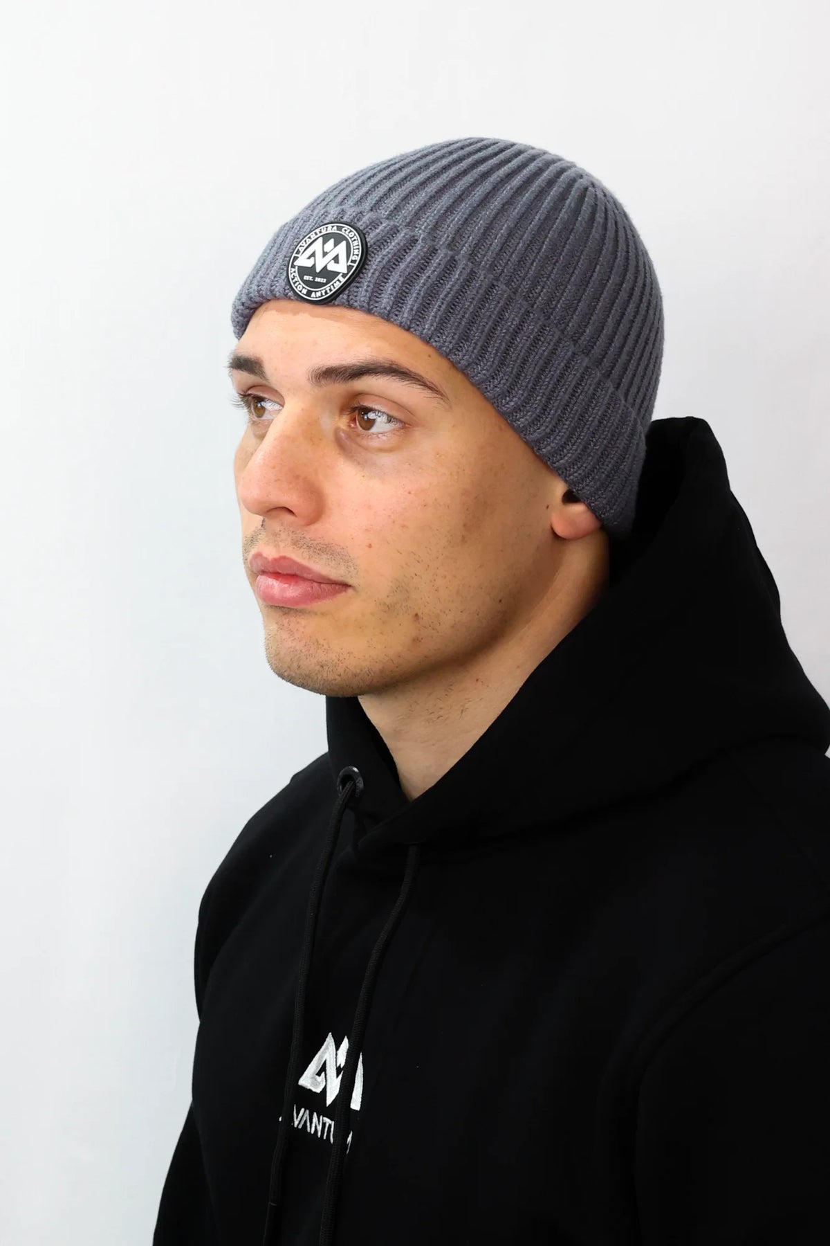 Grey ribbed knit beanie with circular rubber patch logo