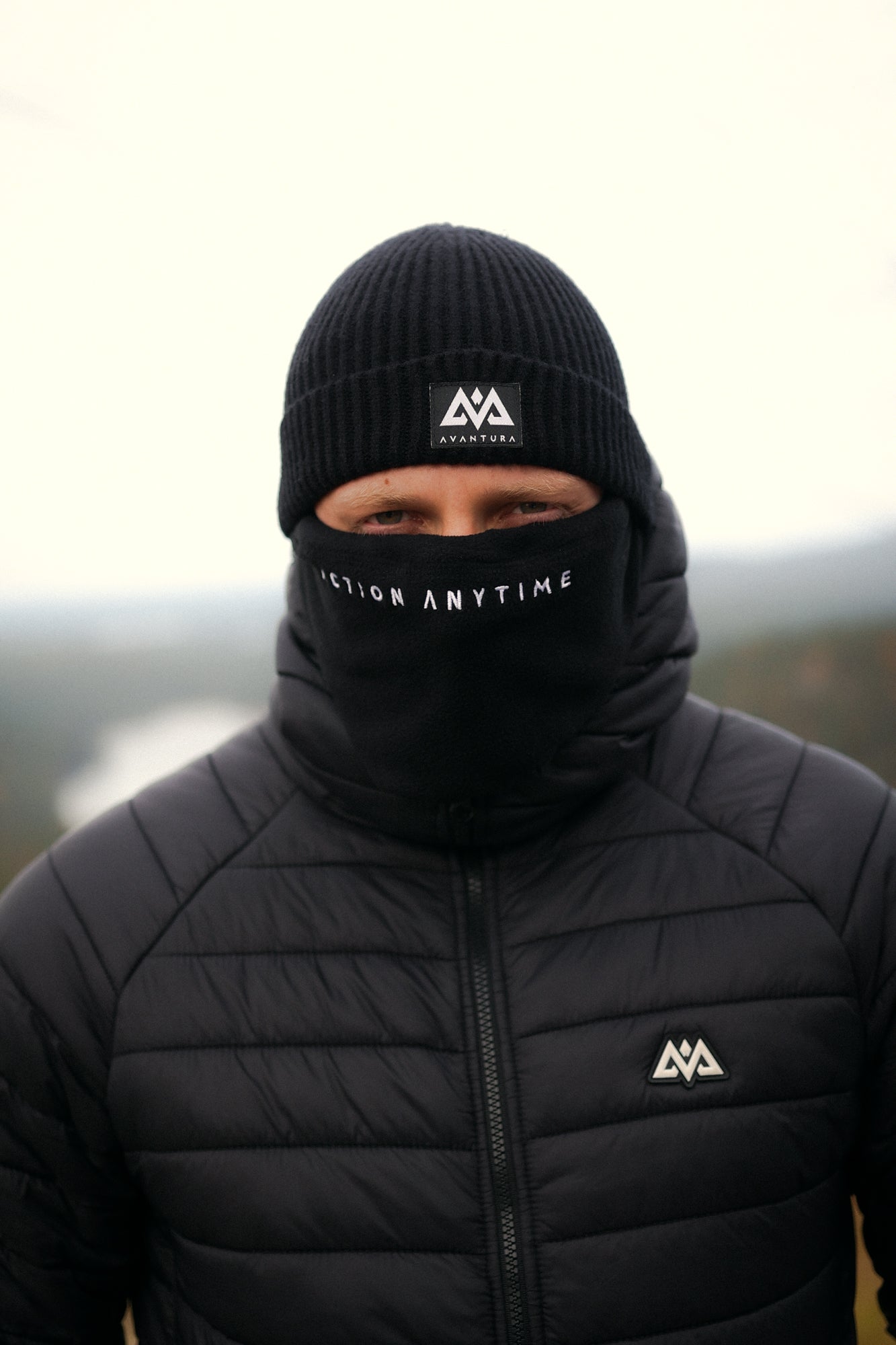 Close-up of black knit beanie featuring woven AVANTURA patch logo