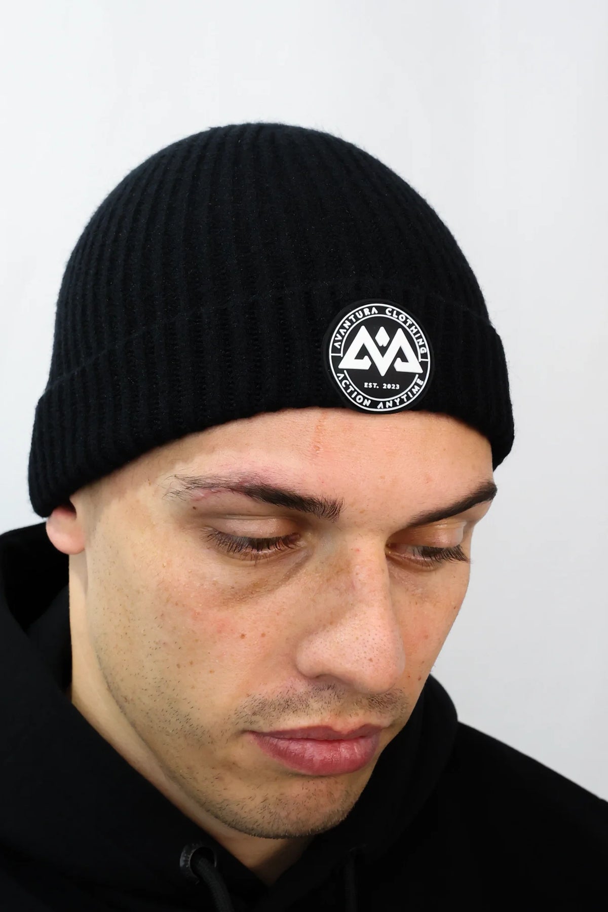 Close-up of Avantura beanie rubber patch with mountain logo and text