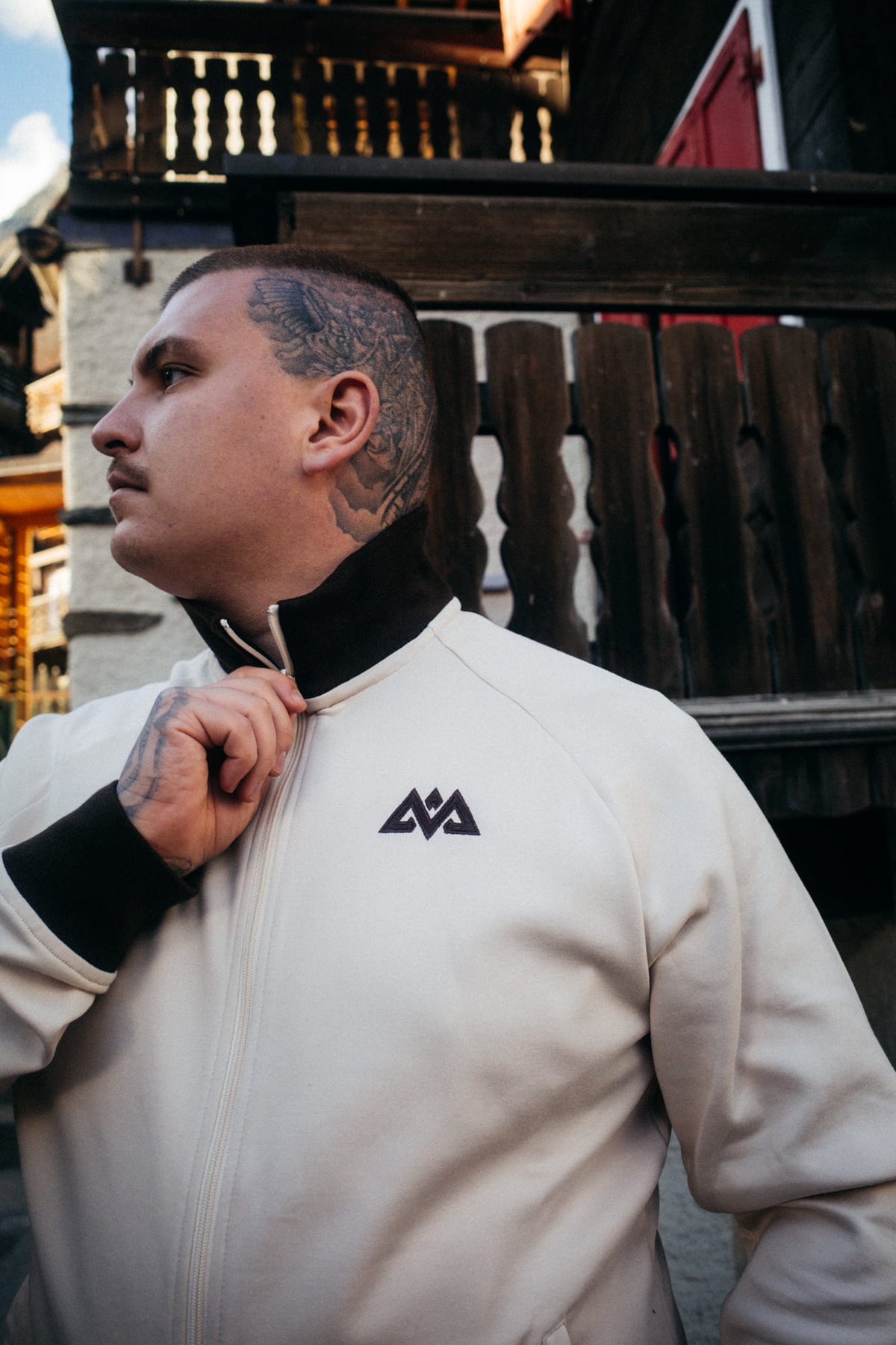 Profilansicht Mann in cremefarbener Trainingsjacke mit Tattoo