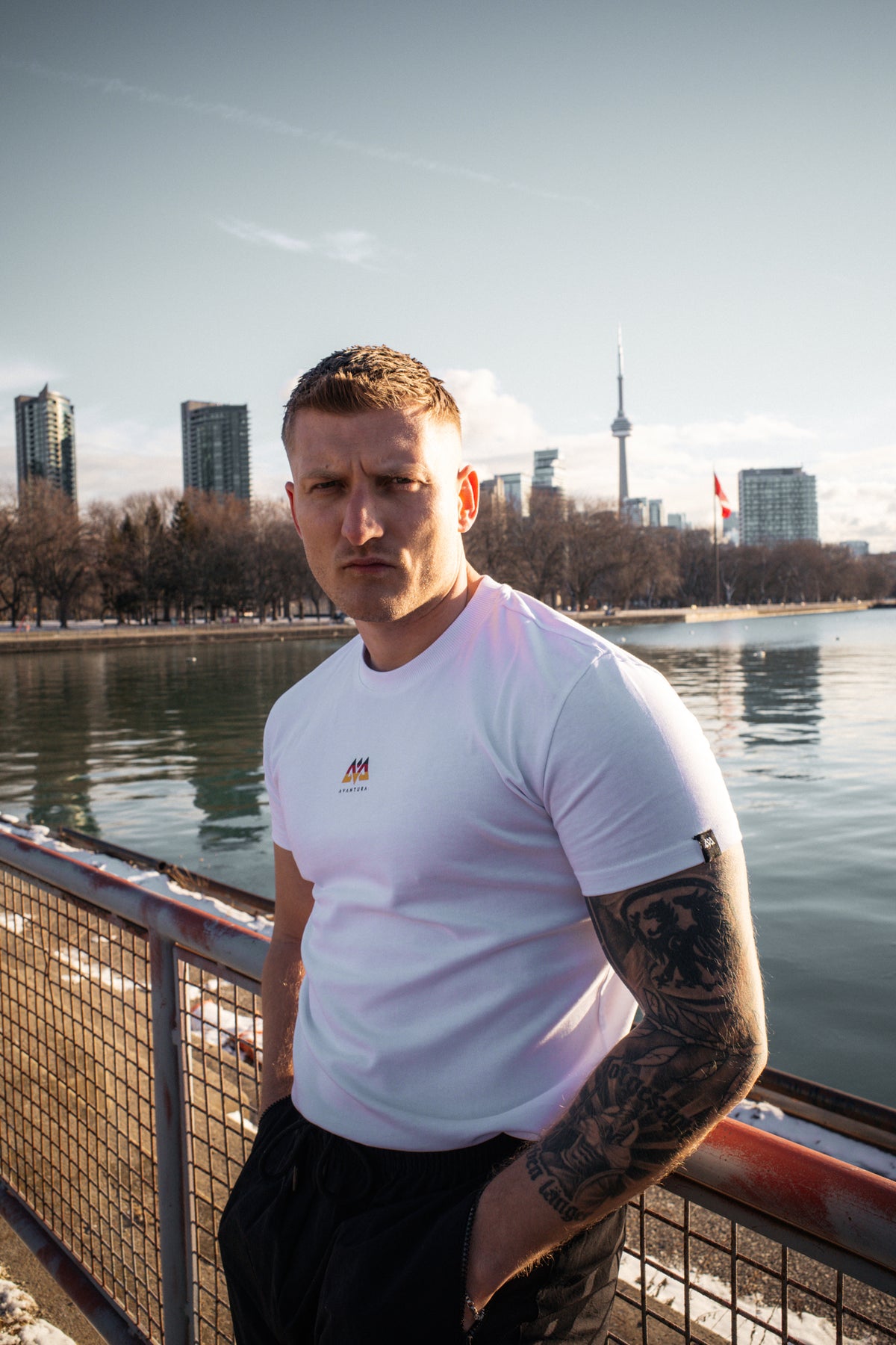 Weißes T-Shirt mit kleinem Ärmel-Label und Brustlogo getragen