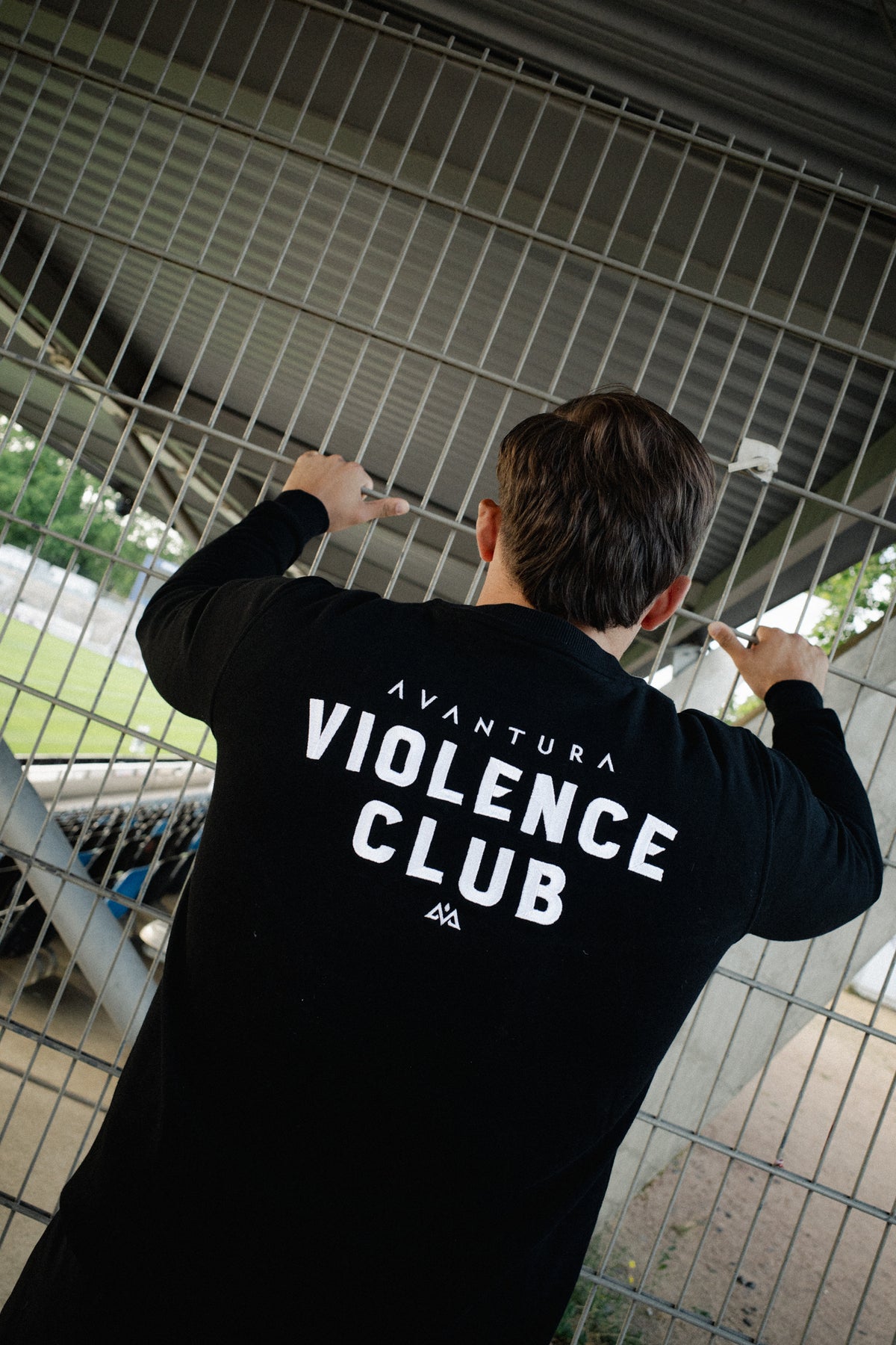 Rear view of black crewneck sweater with back graphic leaning against fence