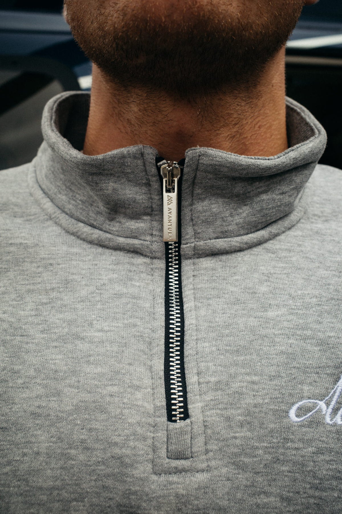 Detail shot of gray half-zip sweater with engraved AVVENTURA zipper