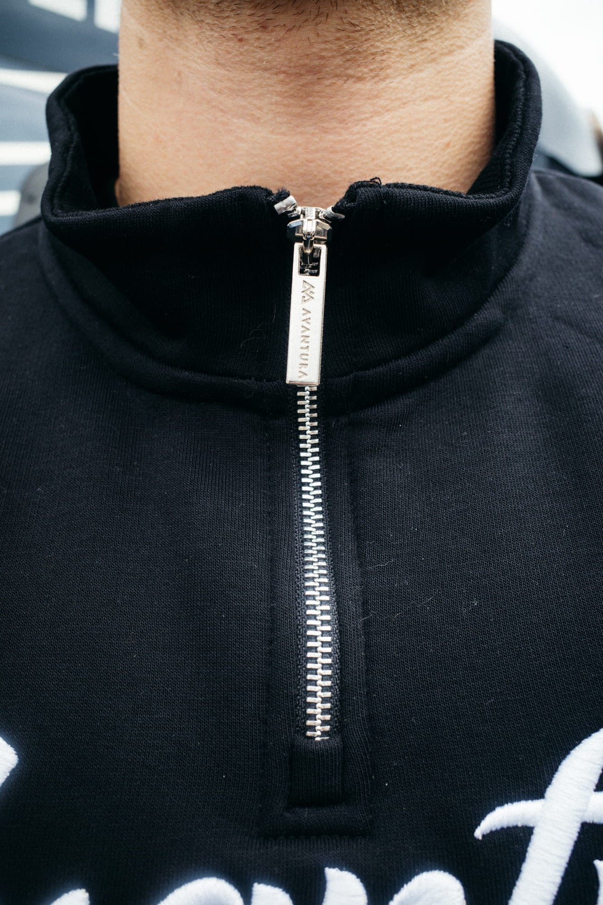 Silver zipper on the stand-up collar of the black sweatshirt