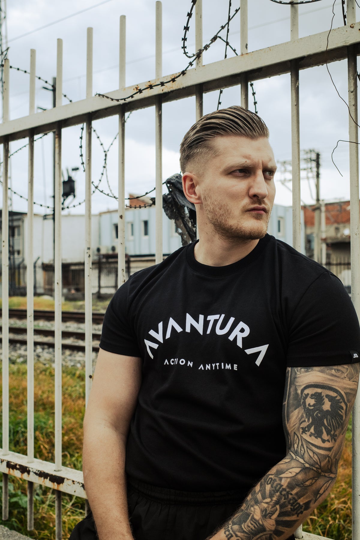 Black Avantura T-shirt with curved white 'AVANTURA' chest print and straight 'ACTION ANYTIME' text