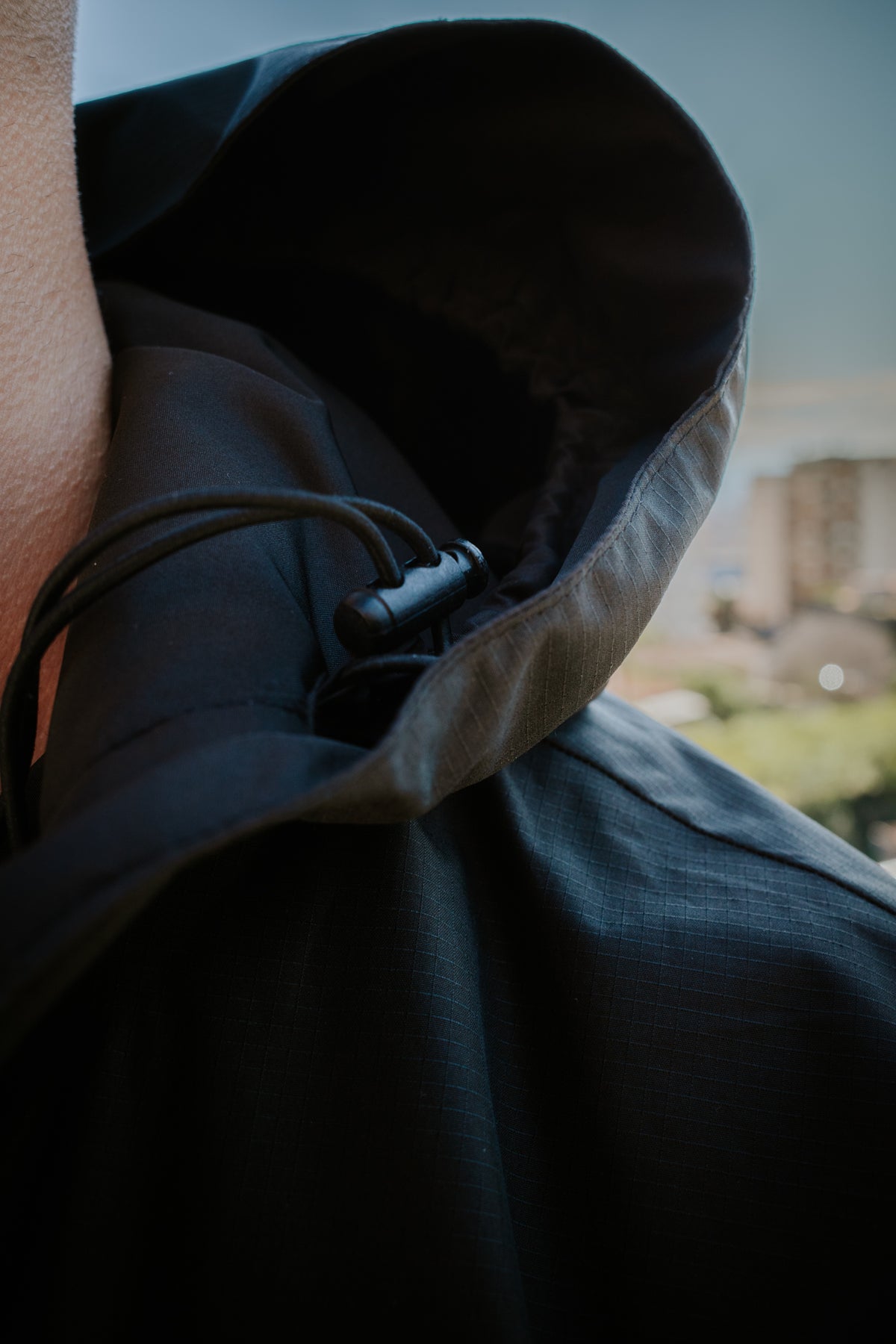 Close-up of hood adjustment toggle and elastic cord on black jacket
