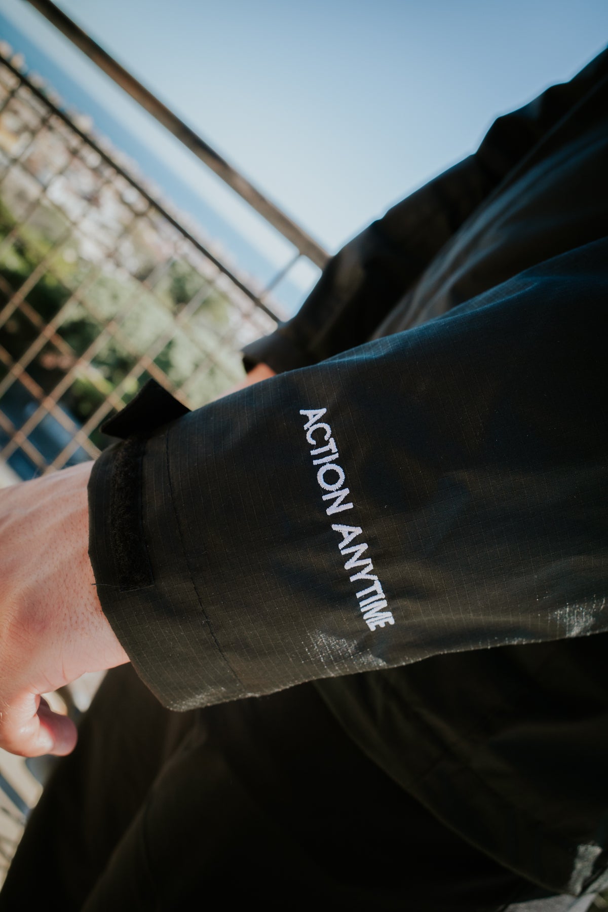Close-up of 'ACTION ANYTIME' embroidered text and Velcro cuff on sleeve