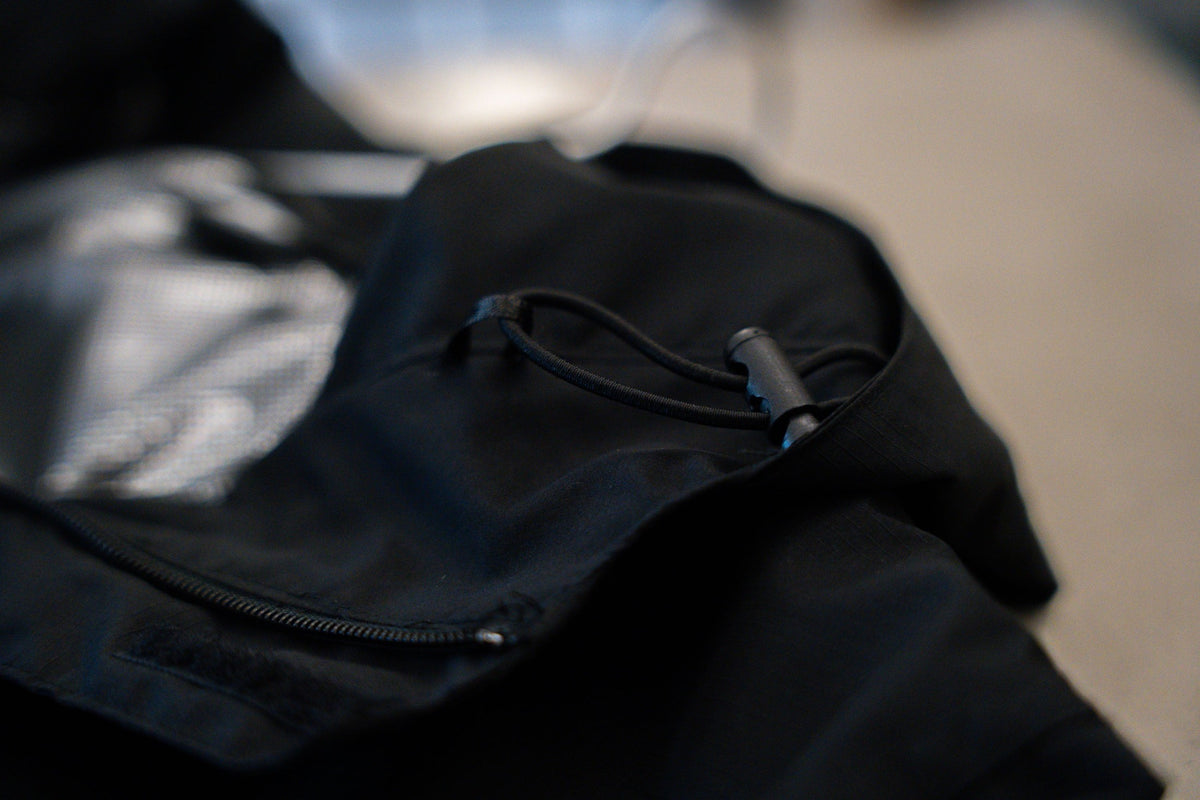Black rain jacket hem with adjustable drawcord and insulated lining detail