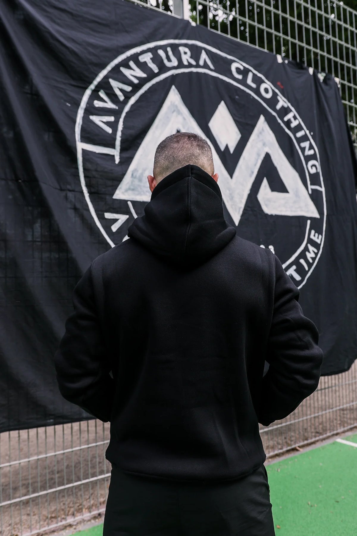 Rückansicht schwarzer Hoodie mit Kapuze vor Markenbanner