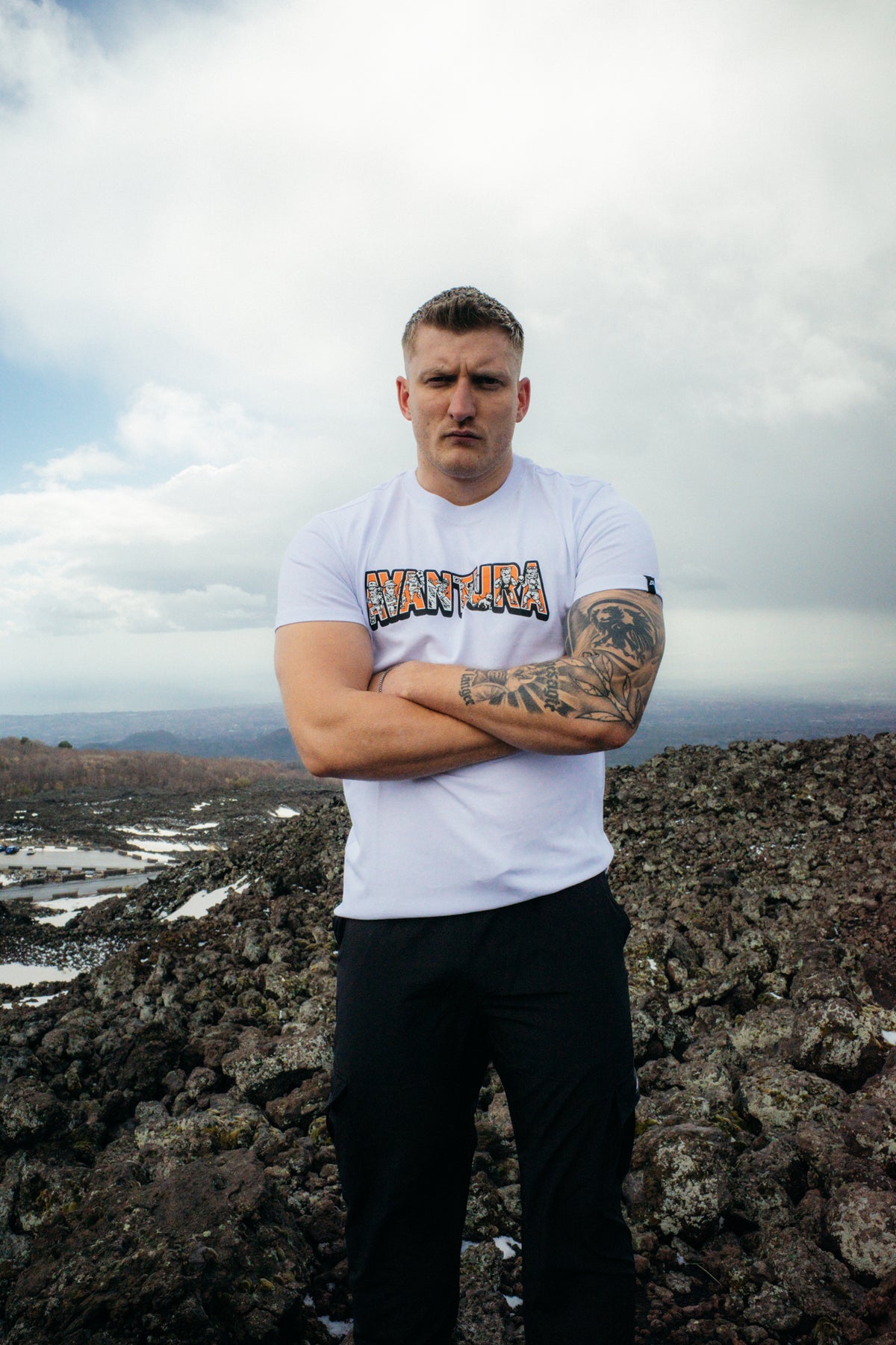 Man on rocky terrain in white short-sleeve T-shirt with centered print