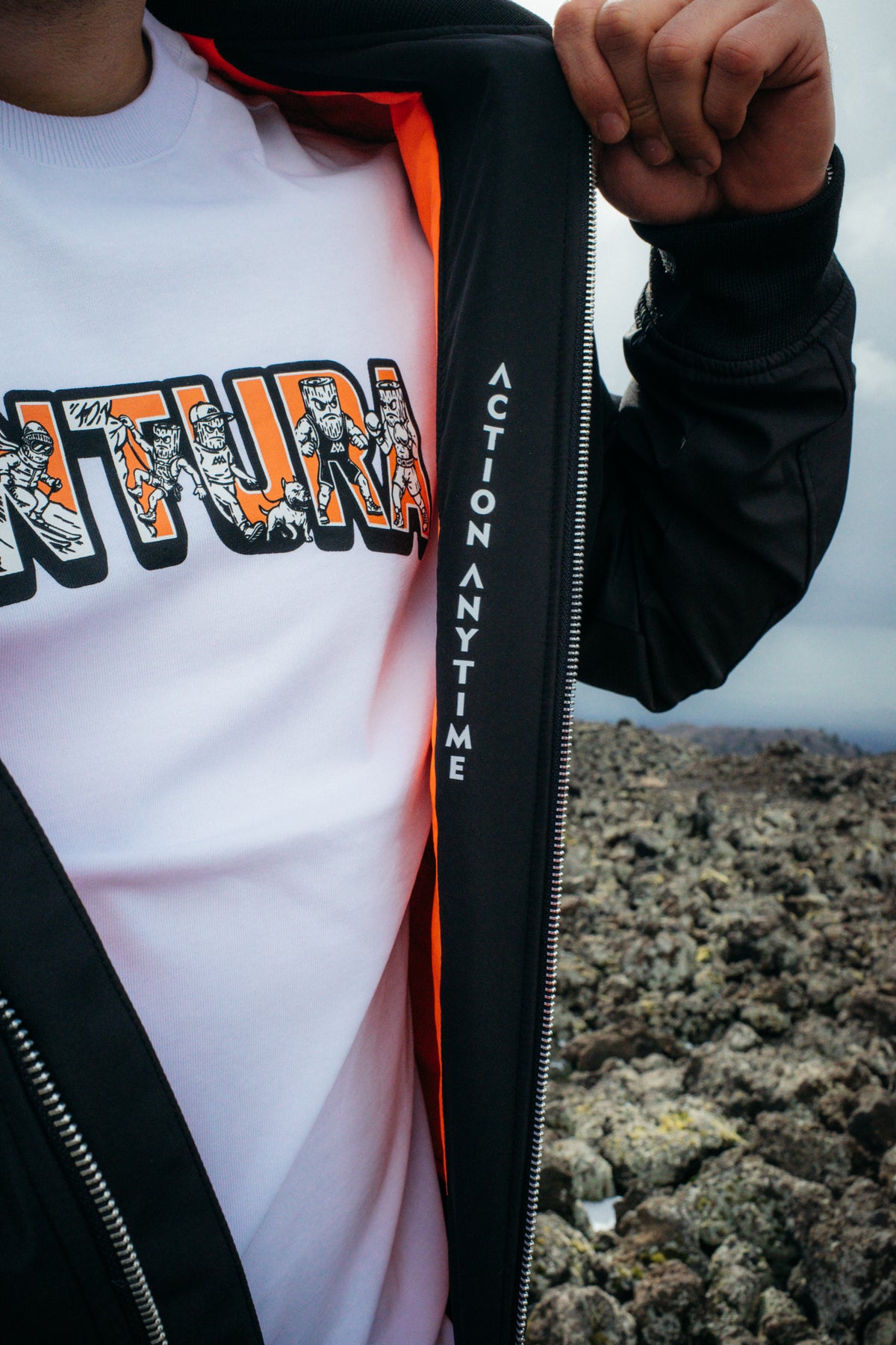Close-up white T-shirt with orange Avventura print under black jacket