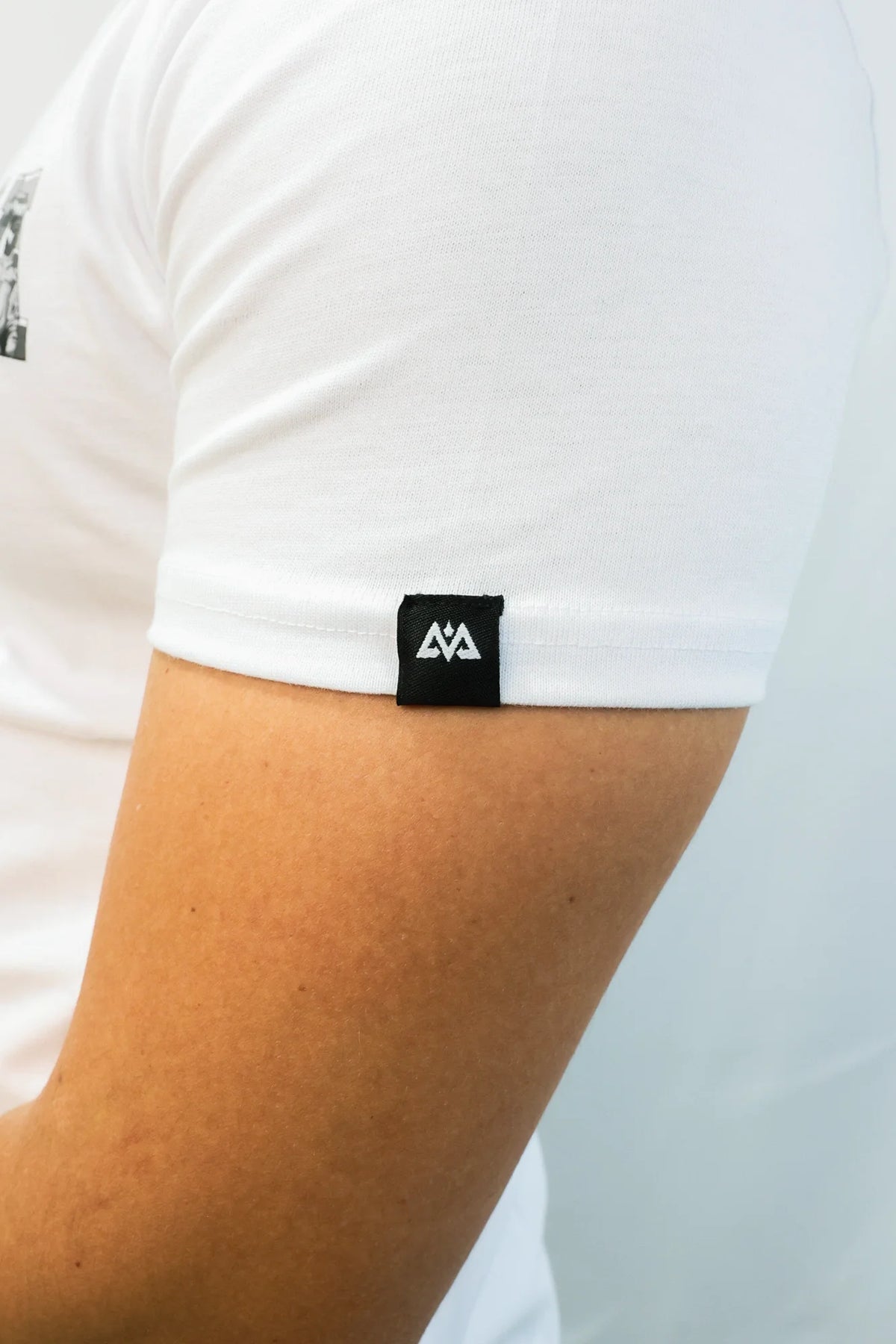 Detail of black woven mountain logo tag on white T-shirt sleeve cuff