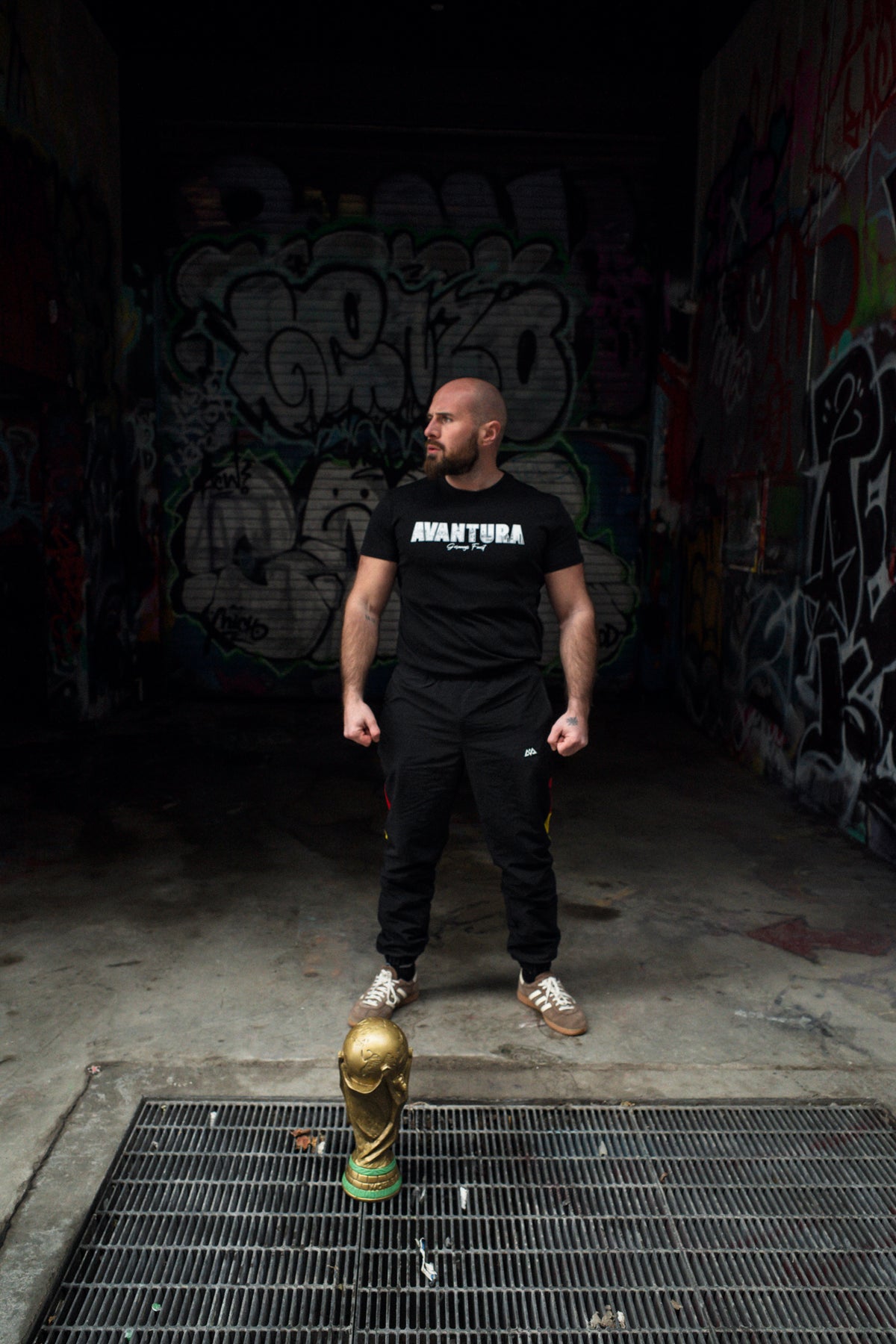 Avantura T-Shirt Schwarz im urbanen Streetwear-Look mit Graffiti-Hintergrund