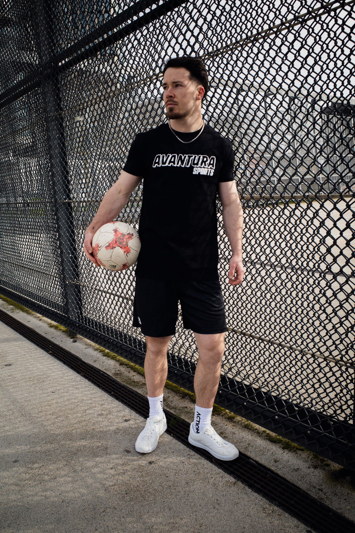 Man holding soccer ball wearing black Avantaura Sports printed T-shirt