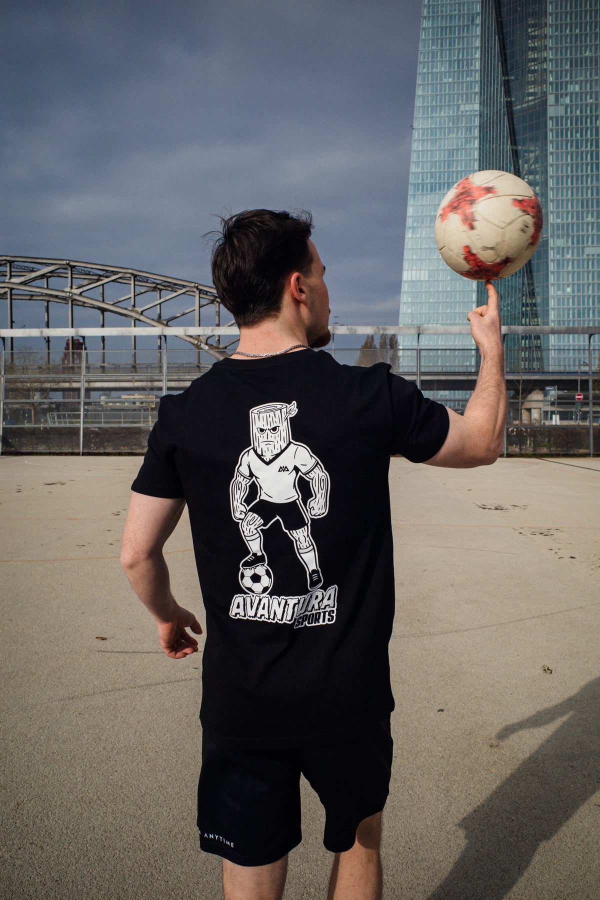 Rear view of black T-shirt showing large white graphic print of soccer character