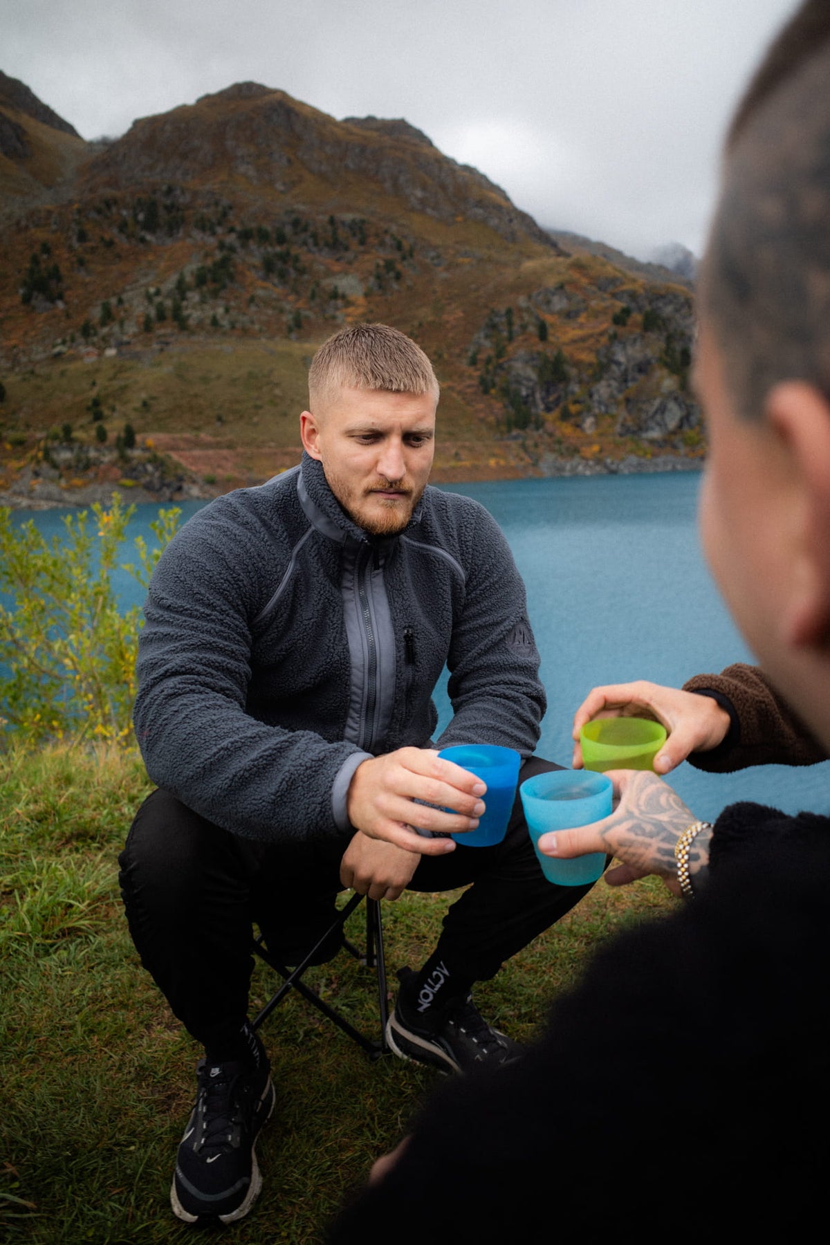 Graue Fleecejacke beim entspannten Trinken am See