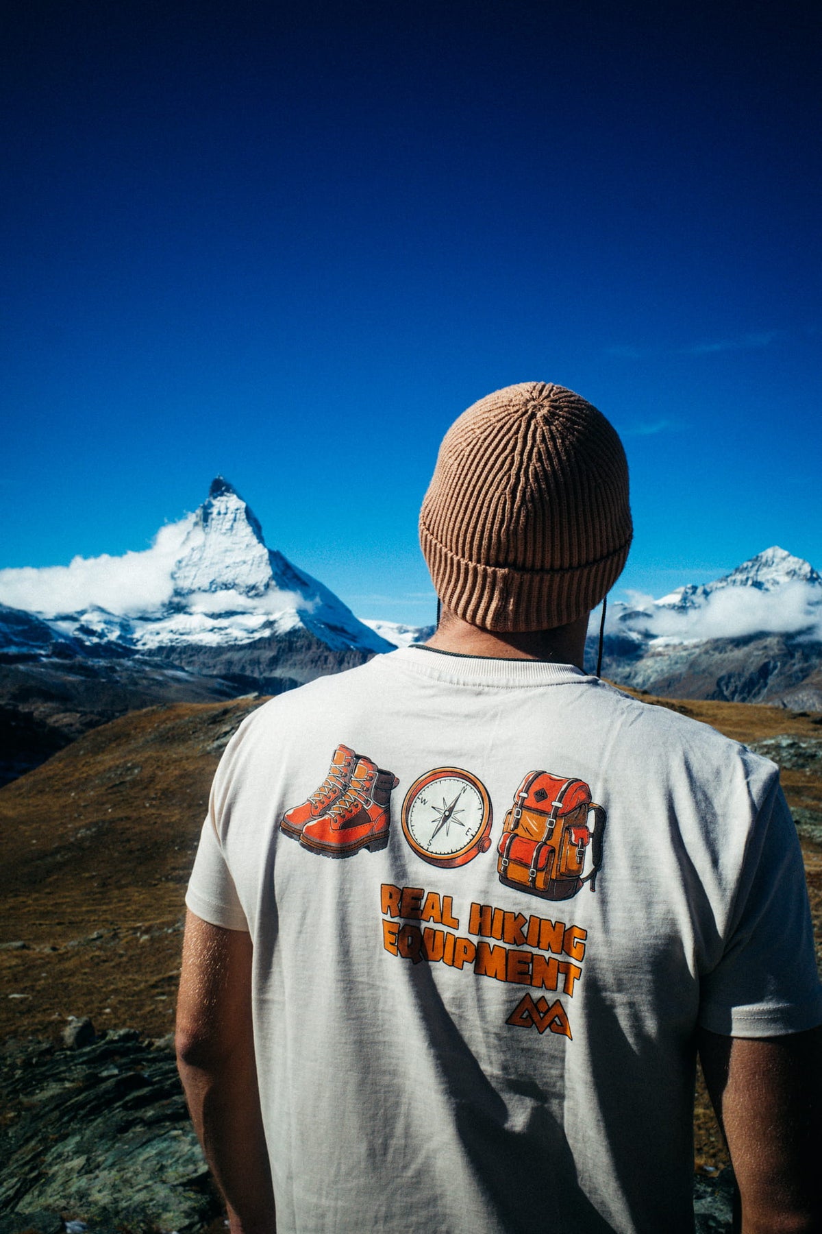 Mann im hellgrauen Hiking T-Shirt vor schneebedeckter Berglandschaft