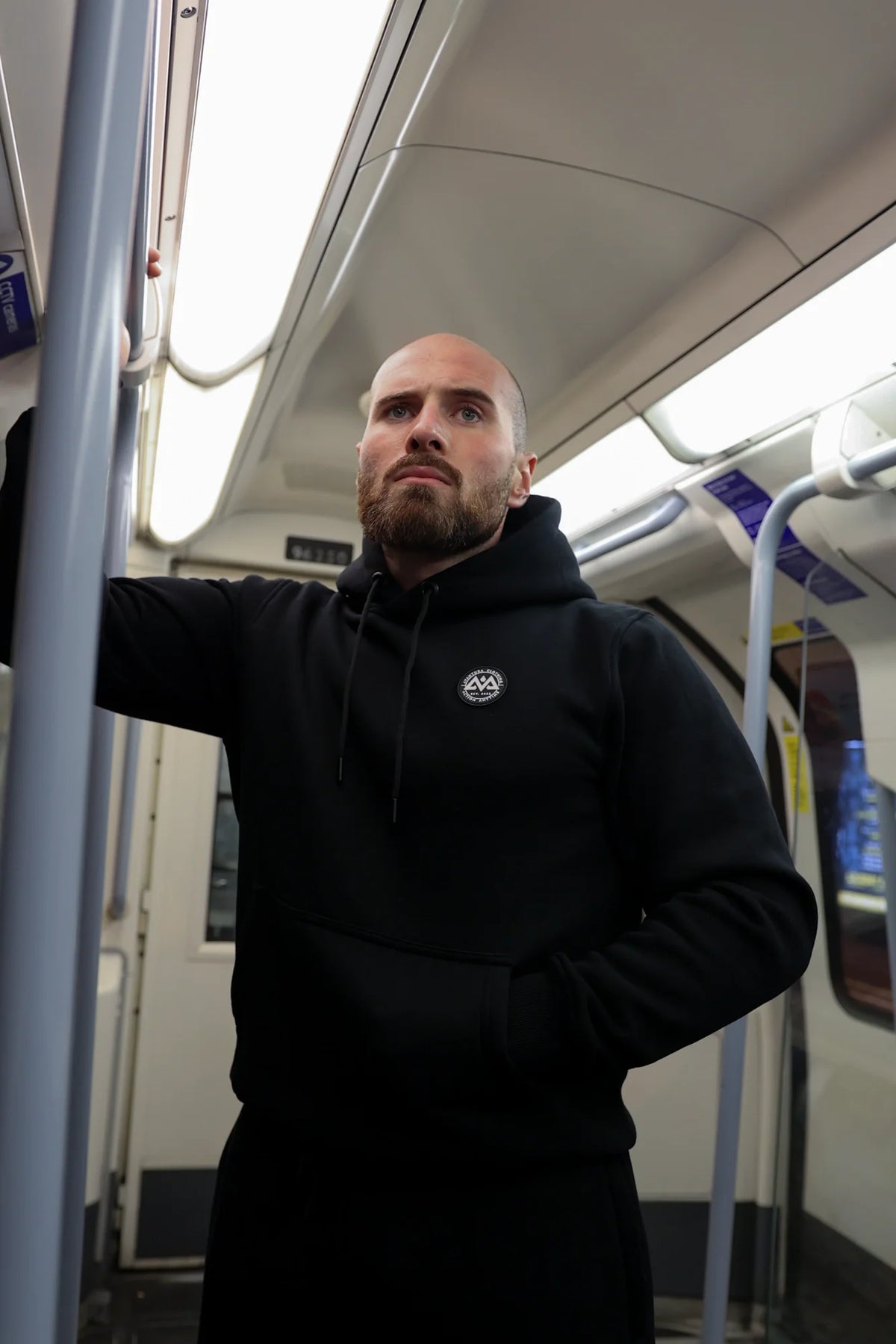 Mann trägt schwarzen Hoodie mit weißem Logo in der U-Bahn