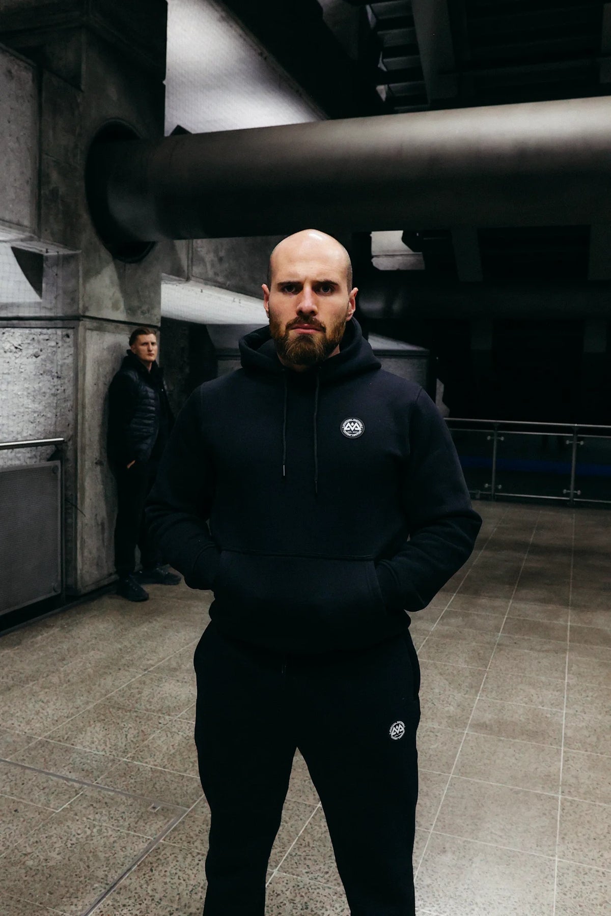 Full outfit look of black hoodie and joggers with matching logos in urban setting