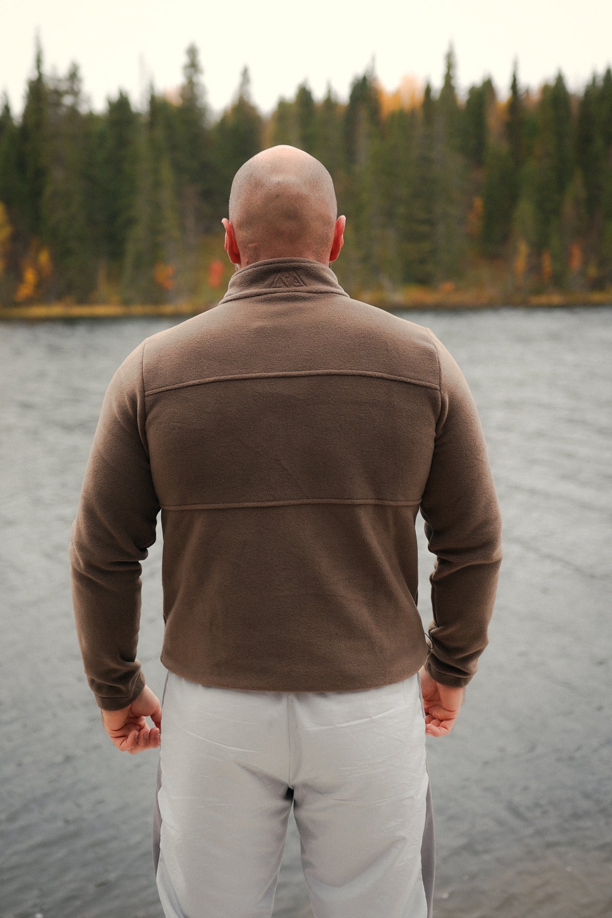 Back view of brown fleece jacket showing seam lines and collar logo
