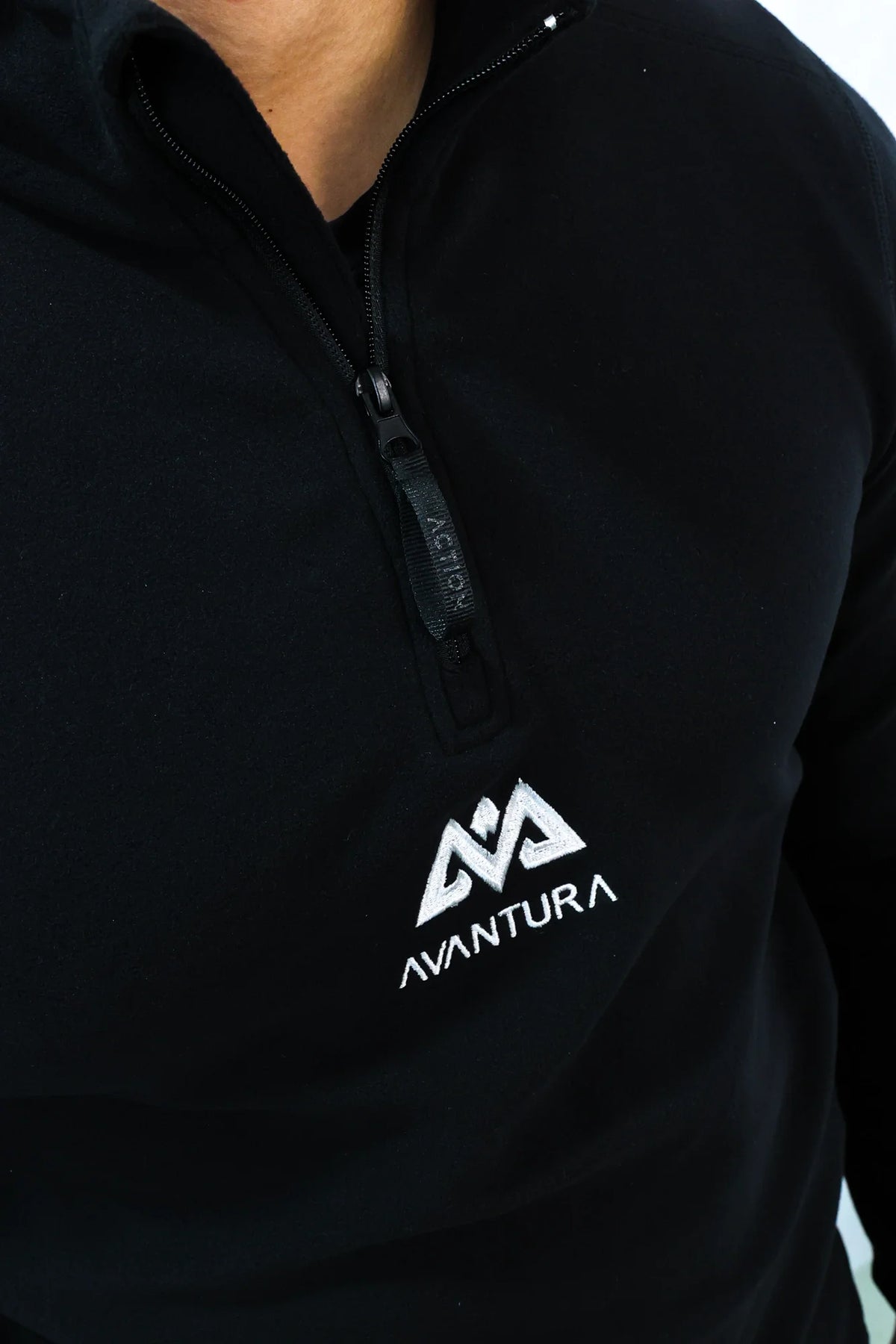 Detailansicht Reißverschluss und gesticktes Logo am schwarzen Fleece