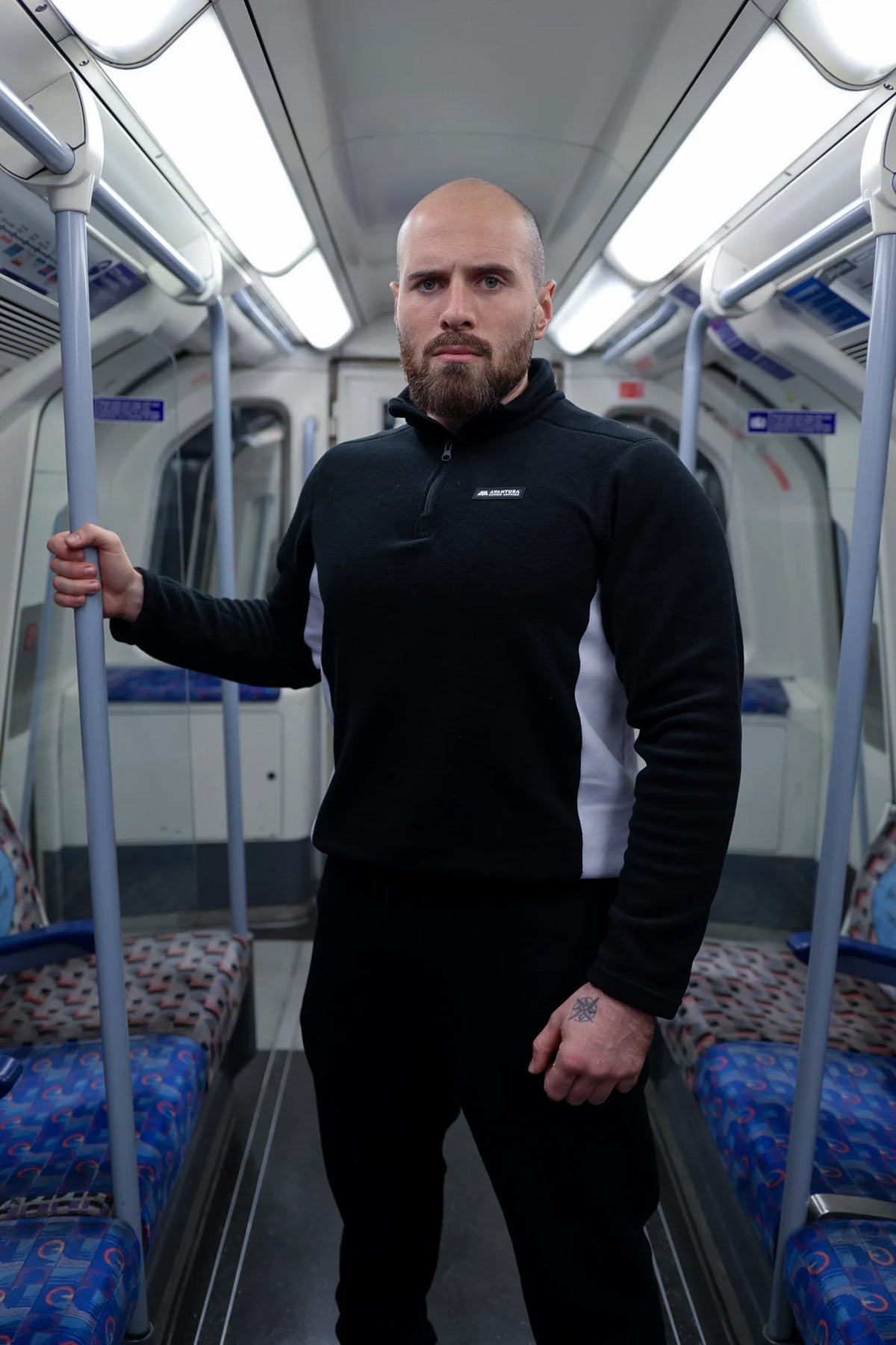 Man wearing black and white half-zip fleece sweater in subway