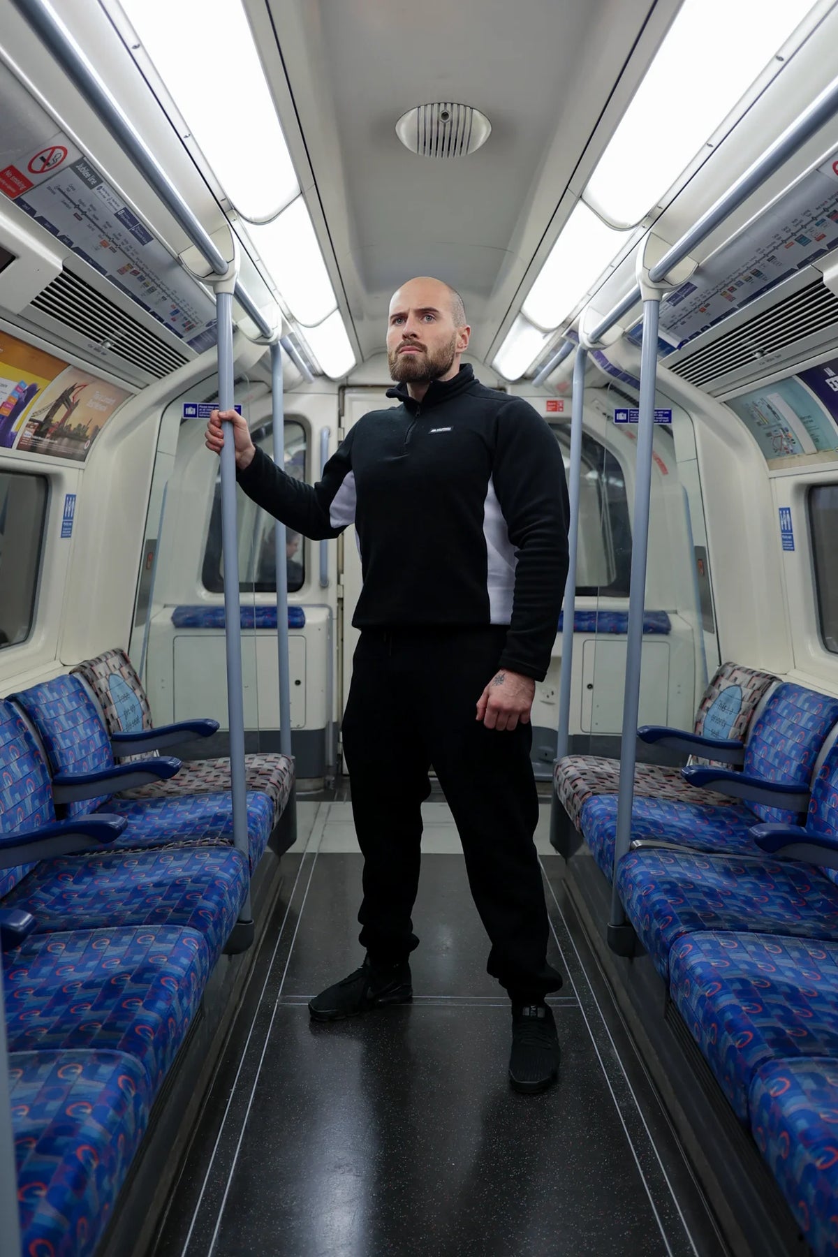 Full body view of man in black half-zip fleece sweater on train