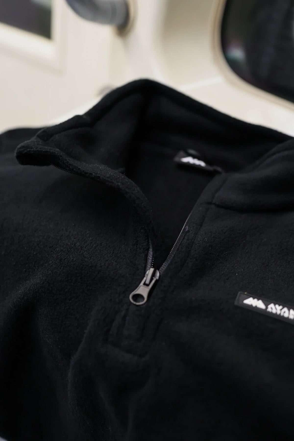 Close-up of black half-zip fleece sweater zipper and collar detail