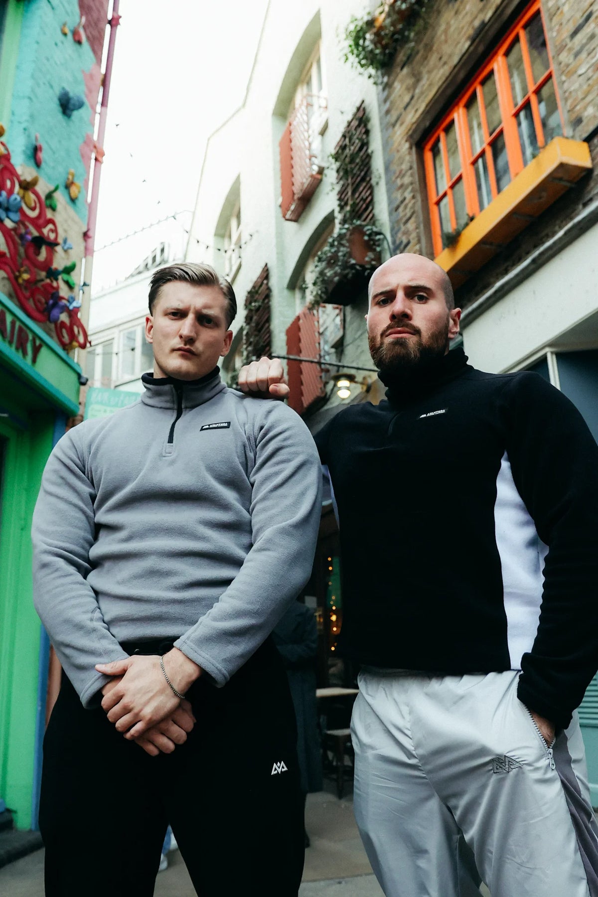 Two men styling grey and black half-zip fleece sweaters outdoors