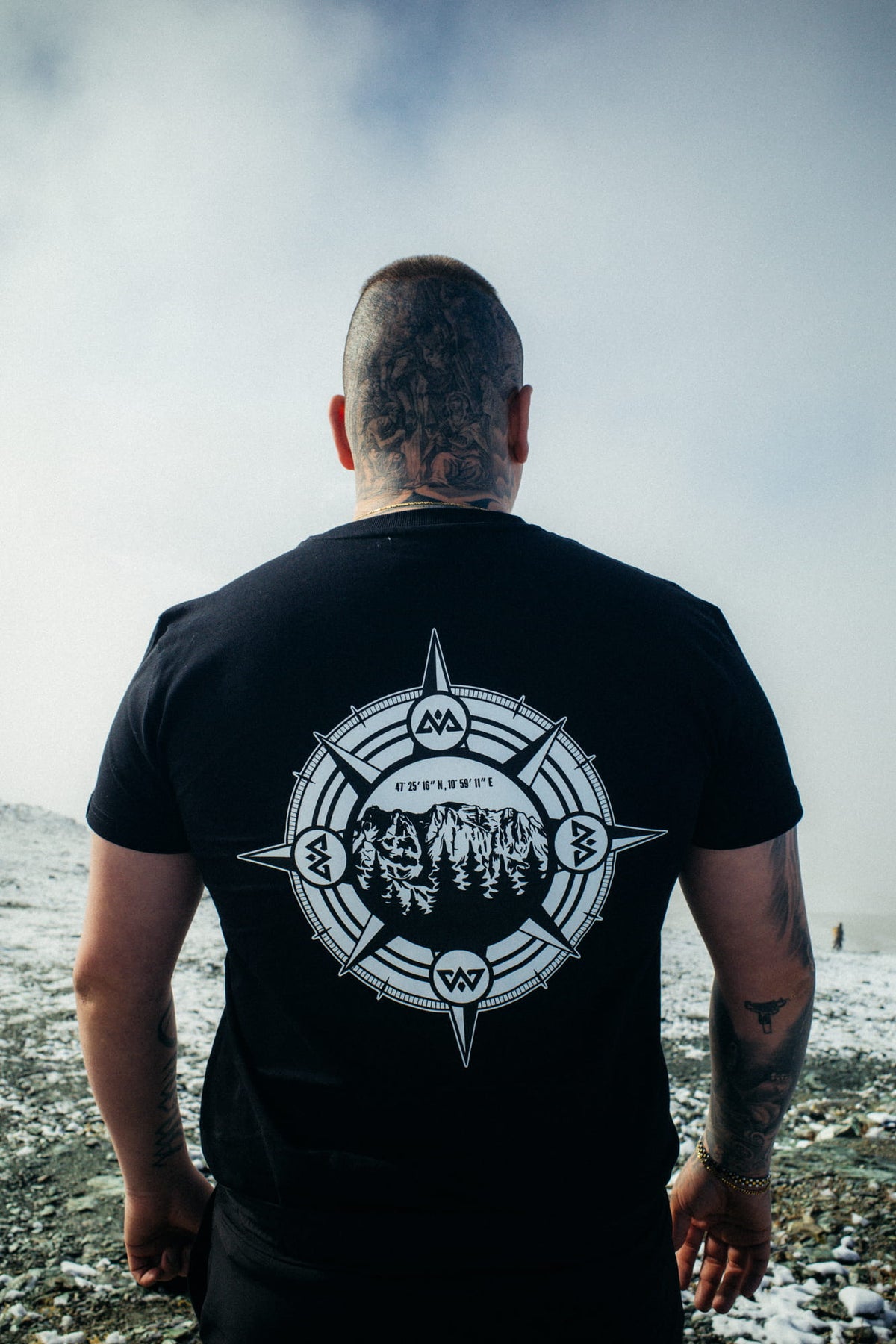 Back view of black T-shirt with white compass and mountain graphic print
