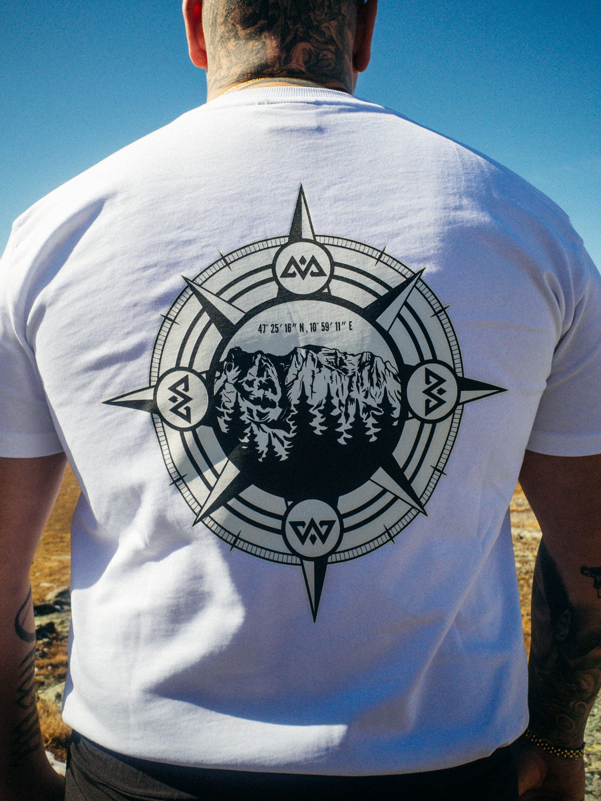 Large black compass back print on white Avantura T-shirt with mountain motif